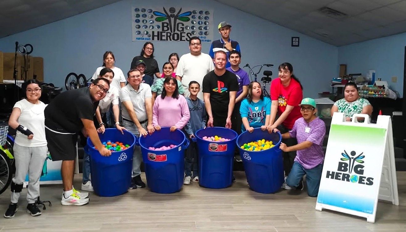 A group of people are posing for a picture in front of a sign that says big heroes