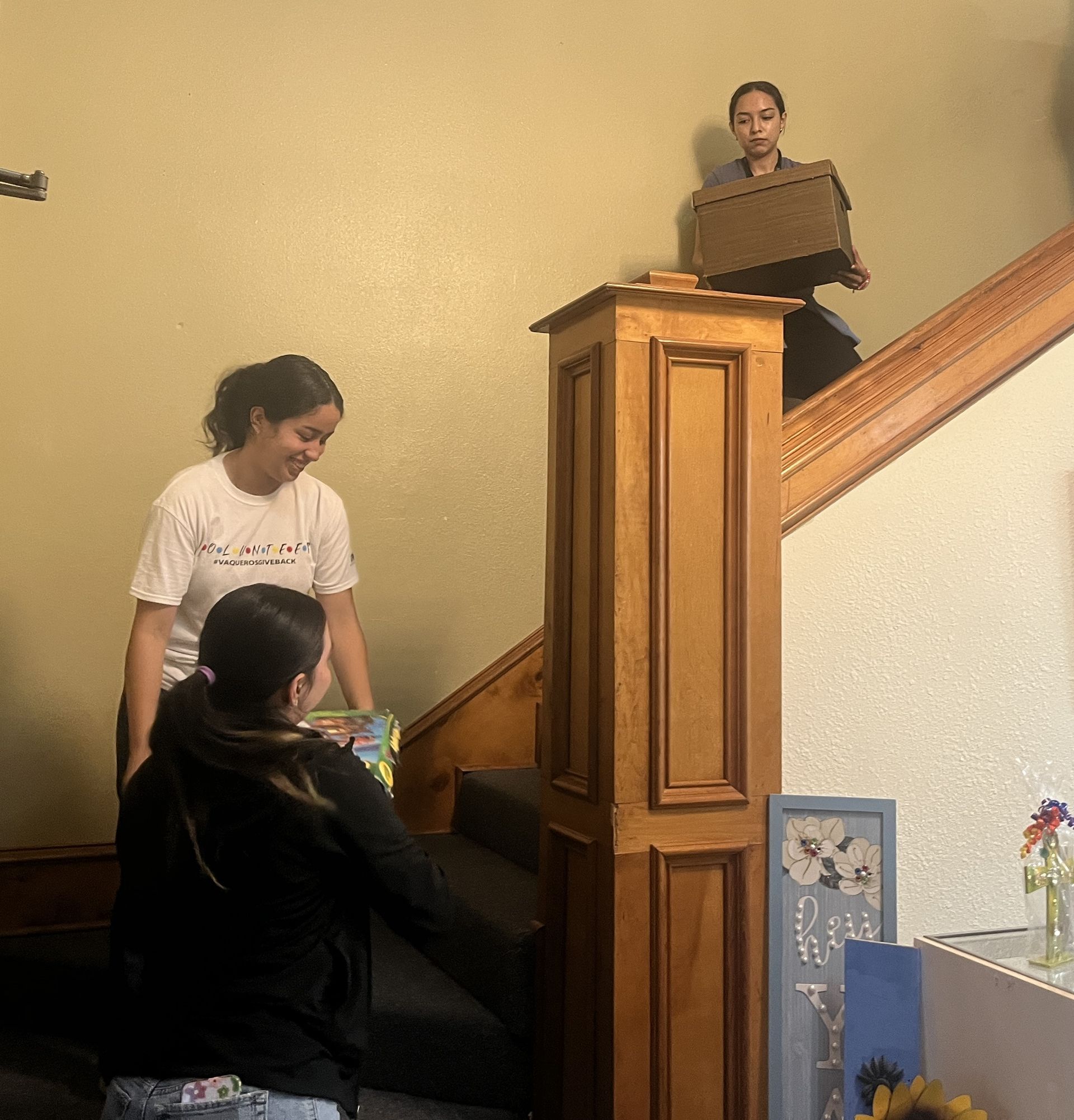A woman is carrying a cardboard box up a set of stairs.