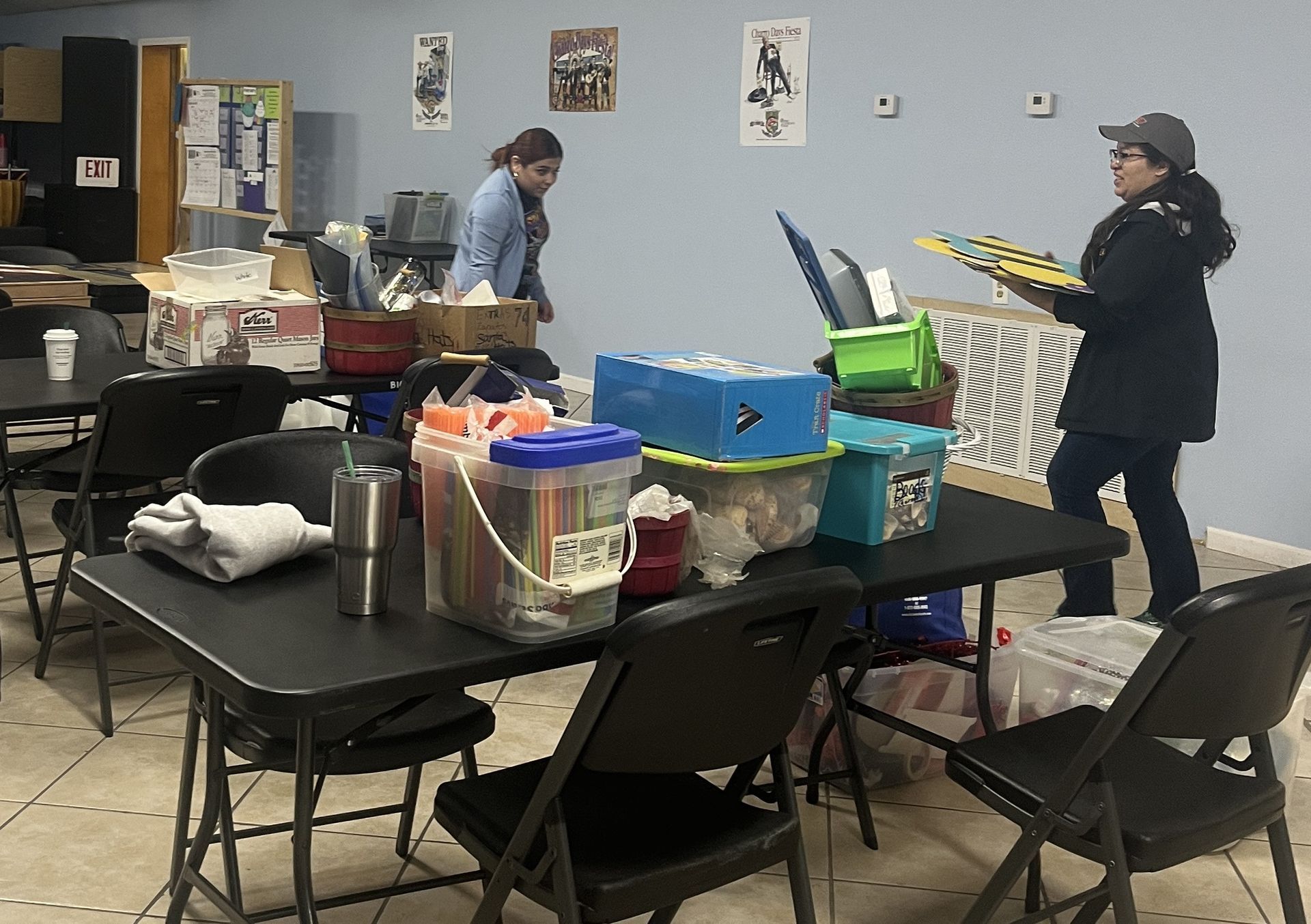 A woman is standing in a room filled with tables and chairs.