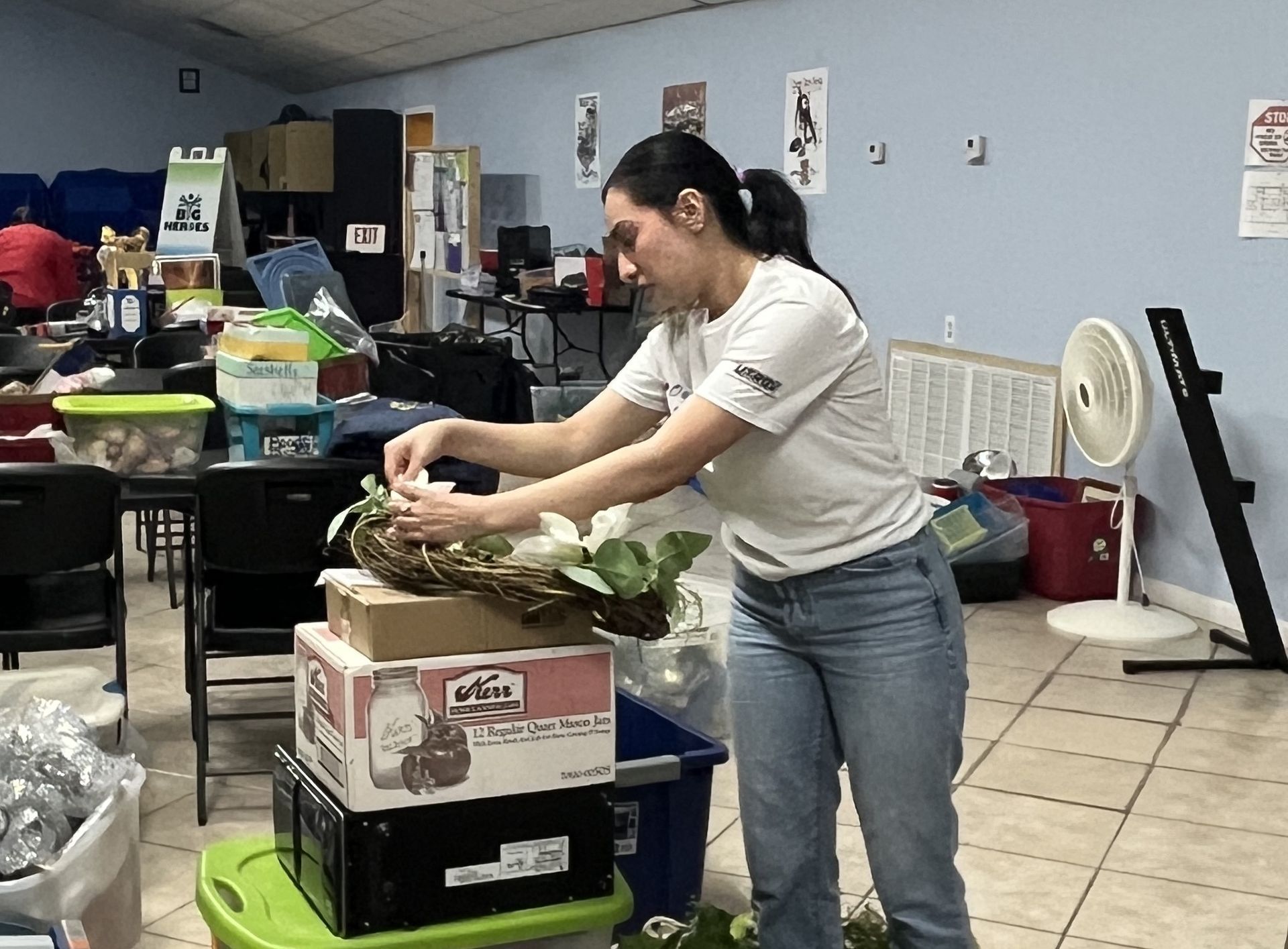 A woman is arranging a wreath on top of a stack of boxes