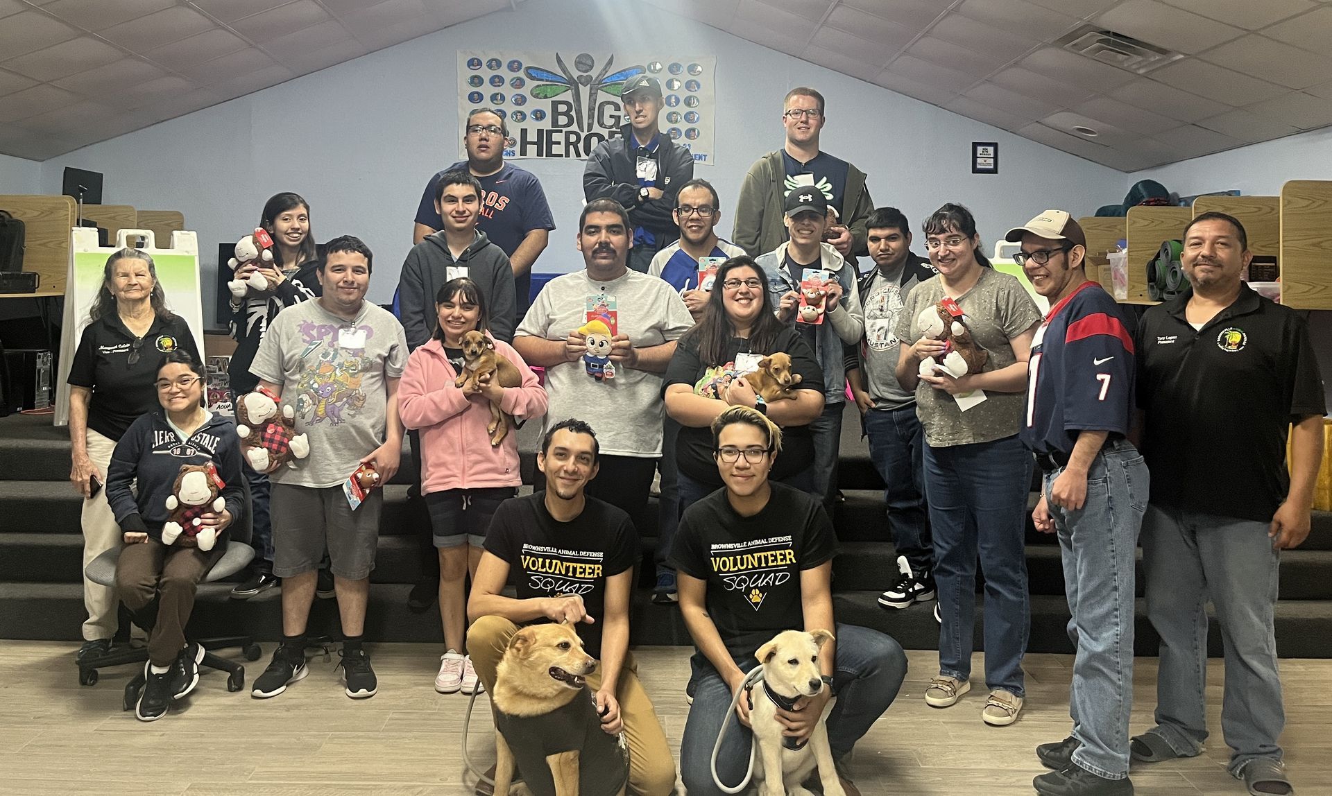 A group of people are posing for a picture with their dogs.