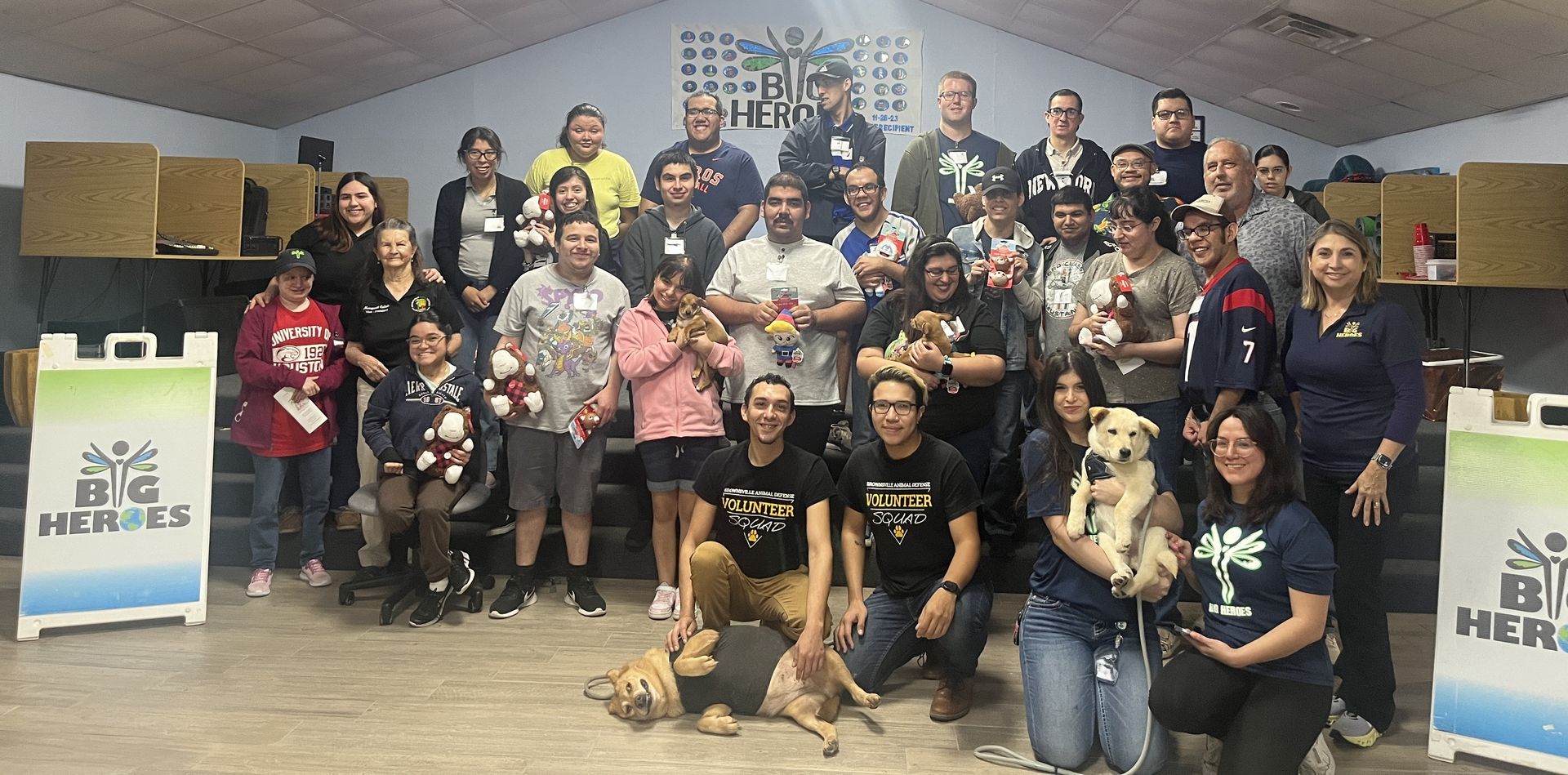 A large group of people are posing for a picture with their dogs.