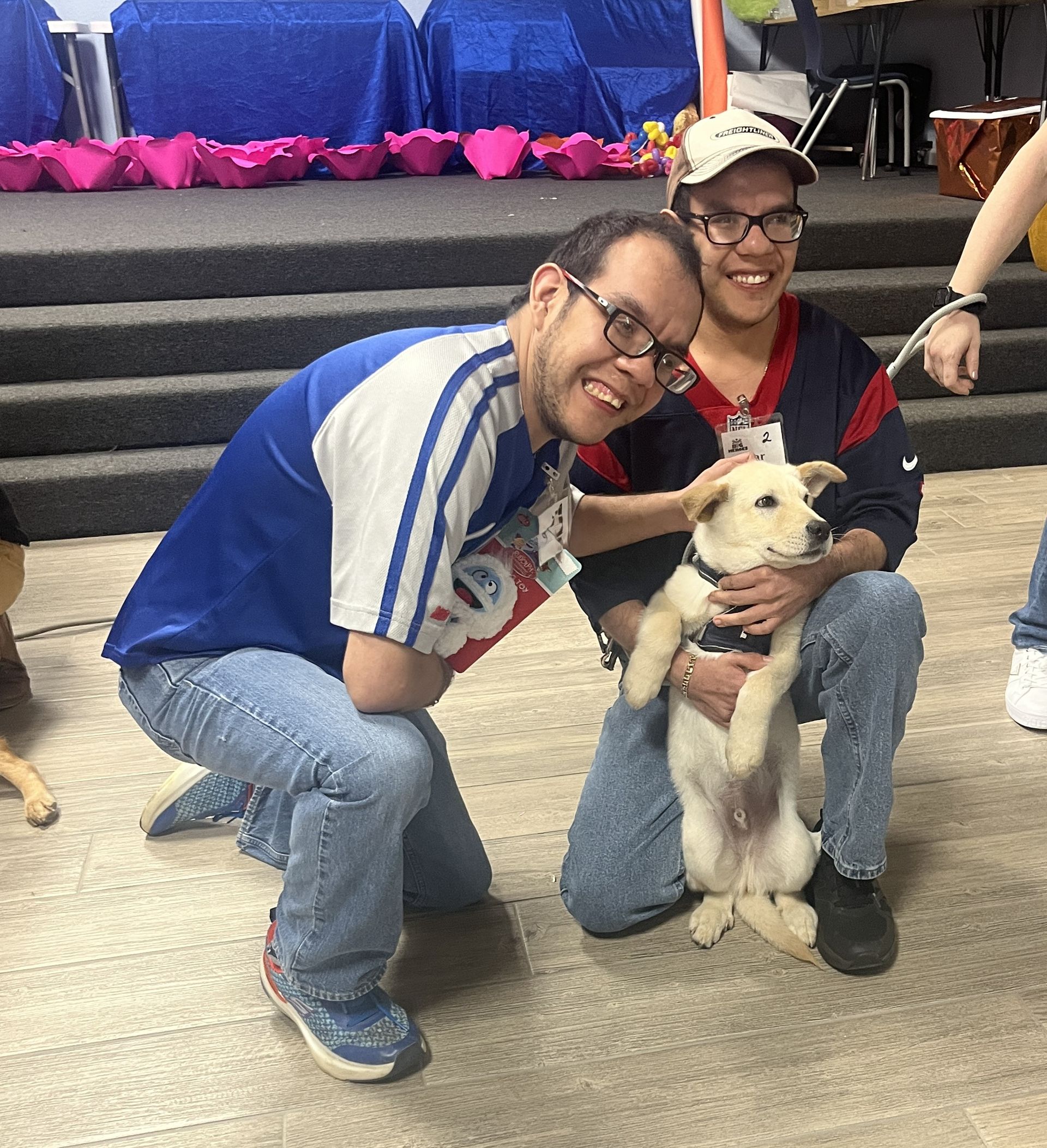 Two men are posing for a picture with a small white dog