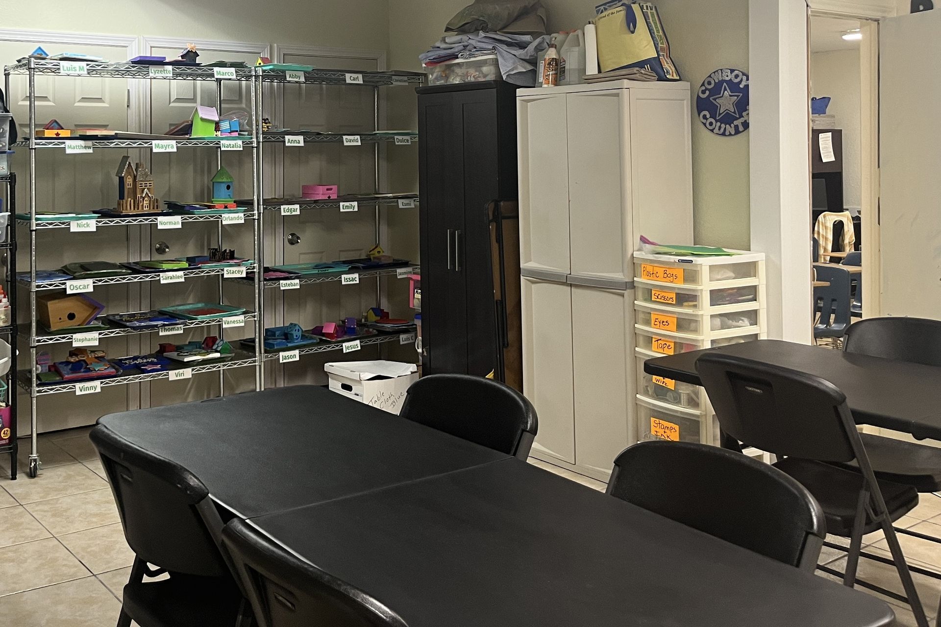 A room with tables and chairs and shelves filled with toys.