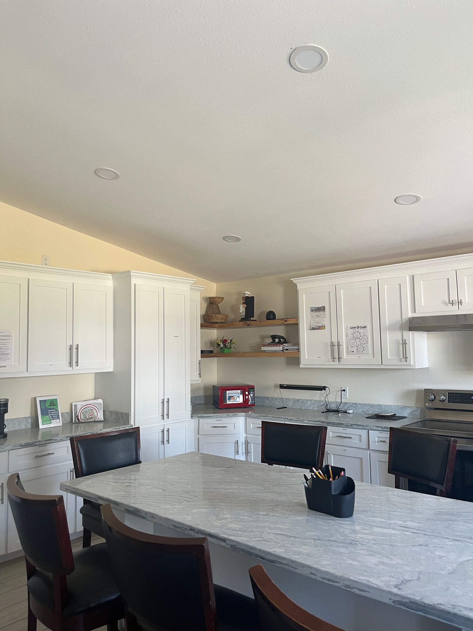 A kitchen with white cabinets and a marble counter top