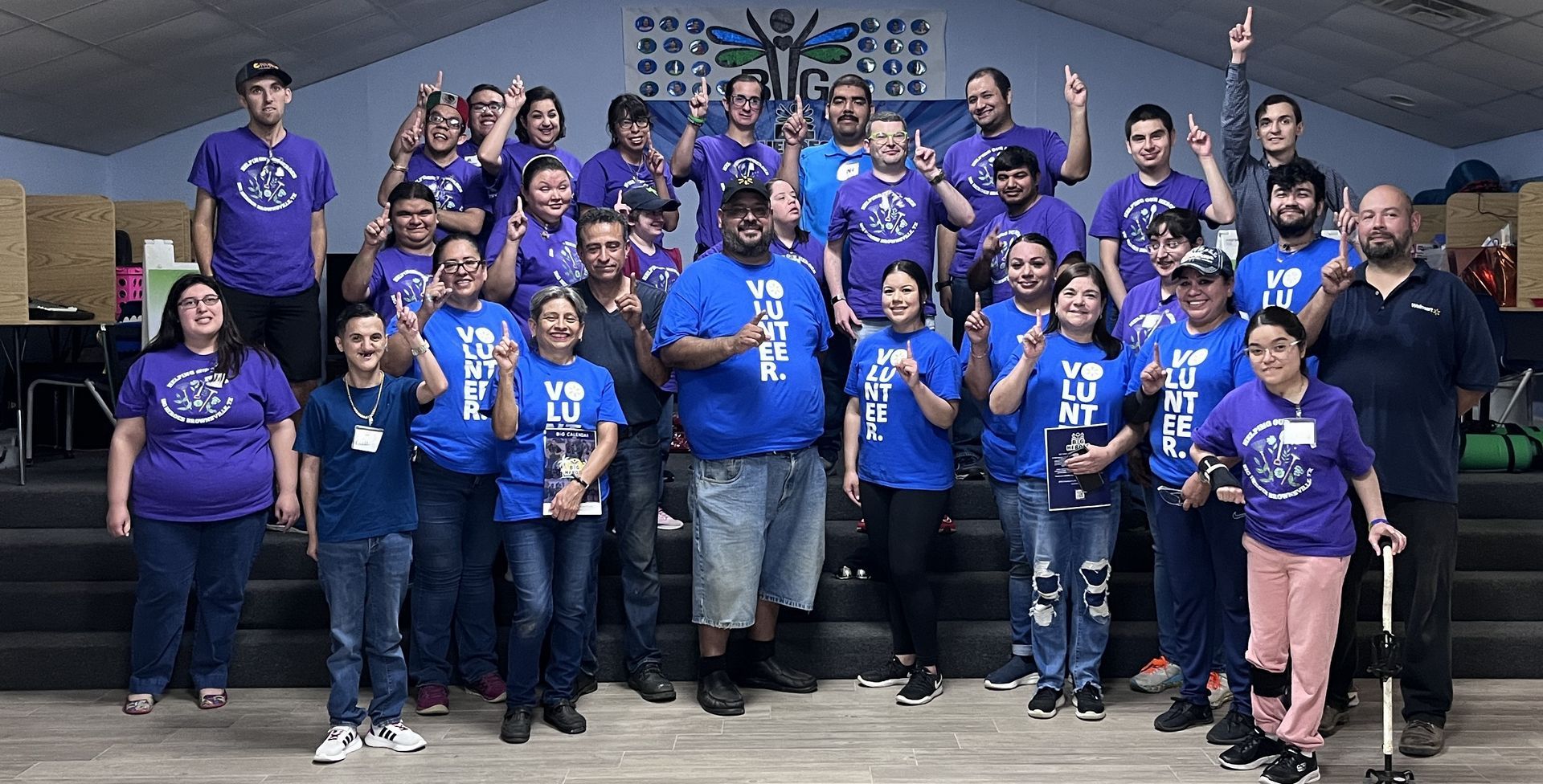 A group of people wearing purple shirts are posing for a picture.