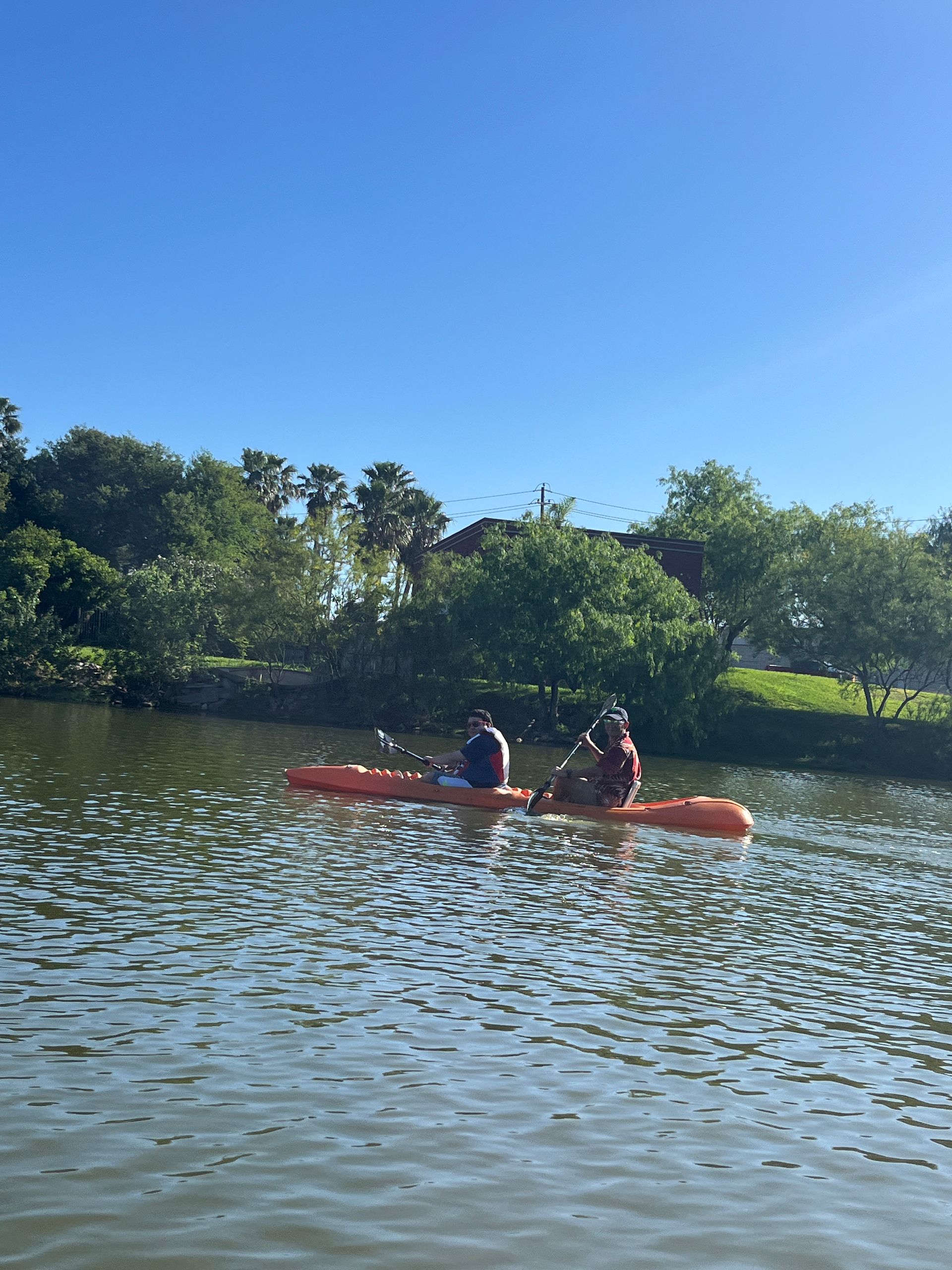 Two people are rowing kayaks on a lake.