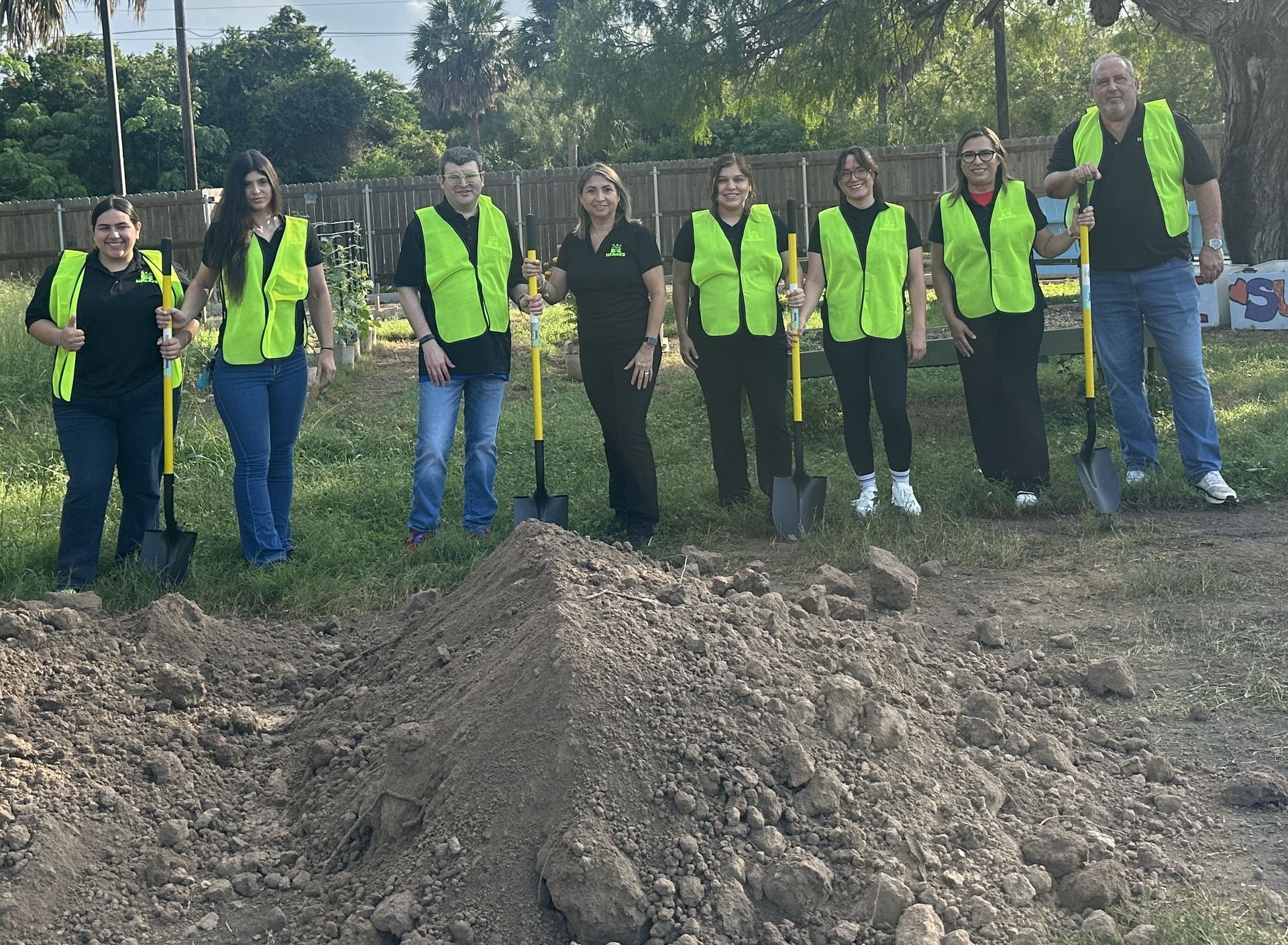 A group of people standing next to each other holding shovels
