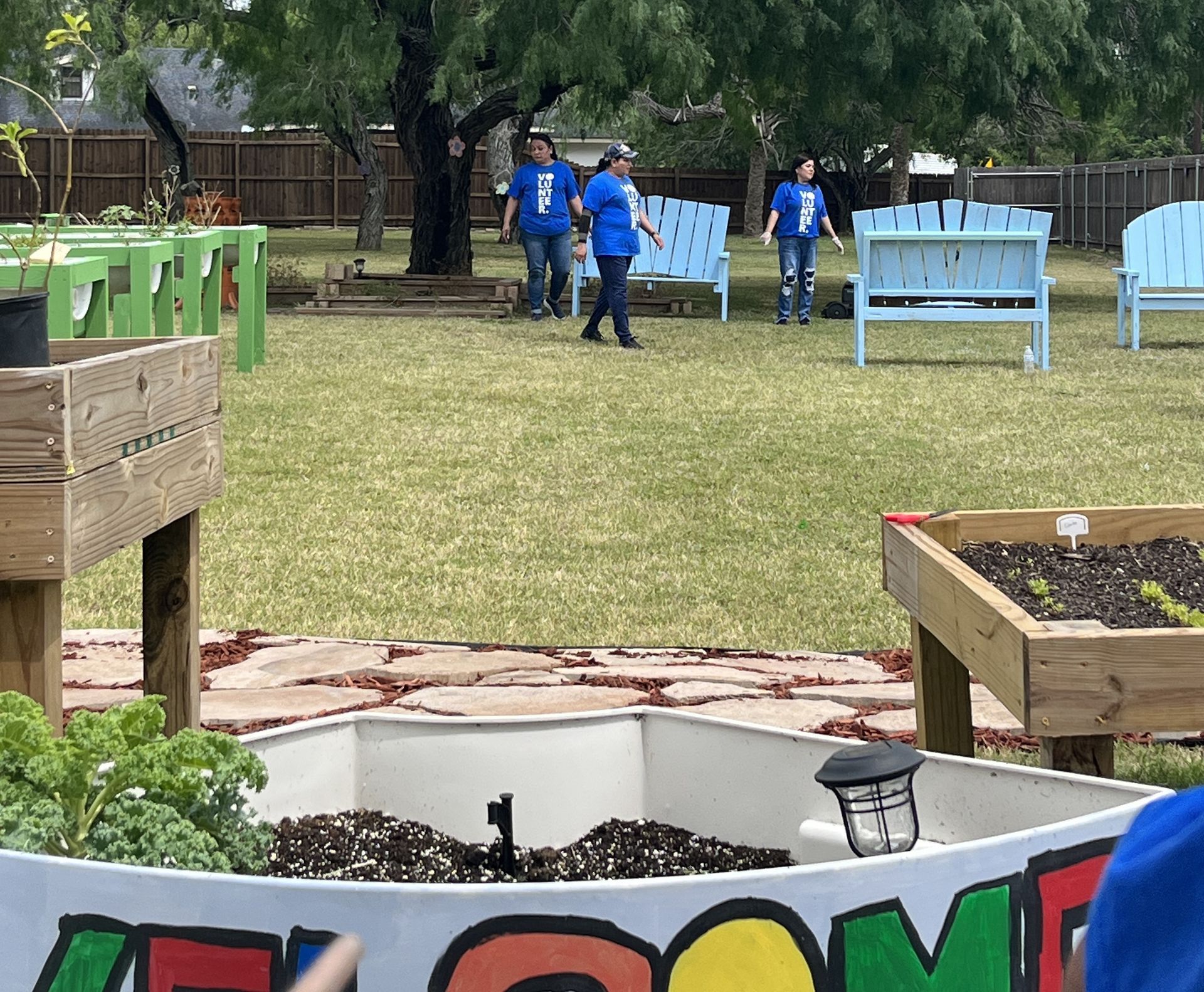 A group of people are walking in a park with a welcome sign in the foreground.