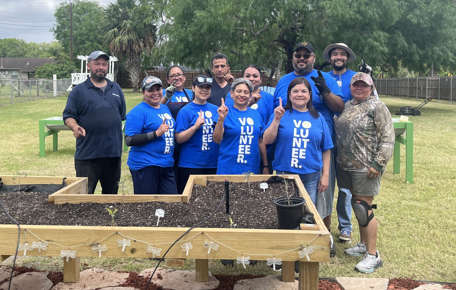 A group of volunteers are posing for a picture in front of a garden bed.