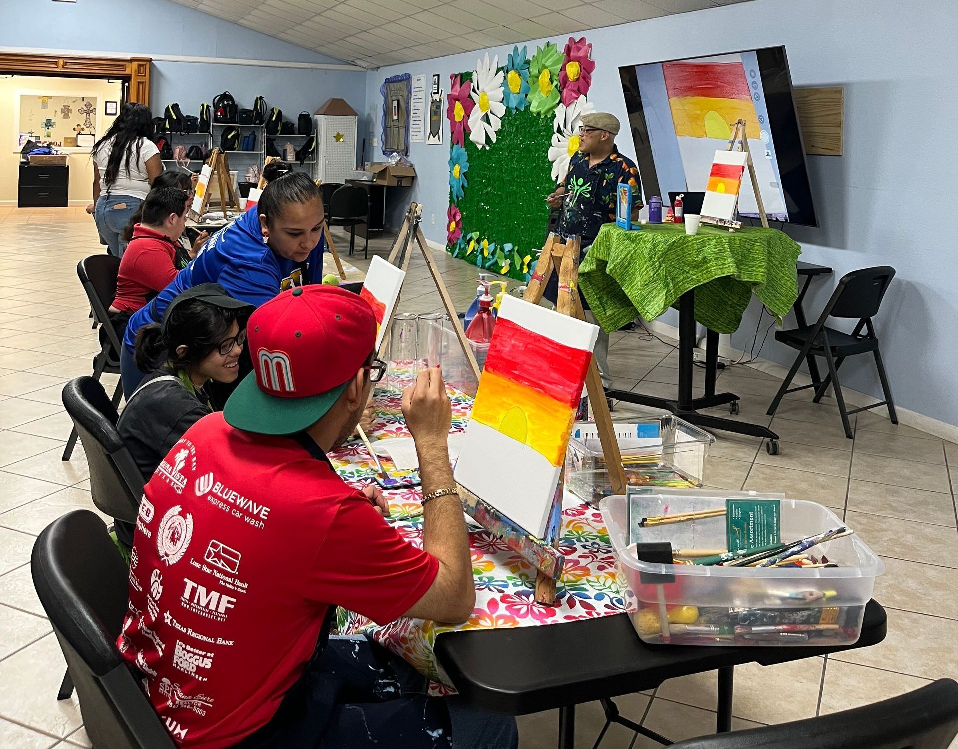 A group of people are sitting at a table painting.
