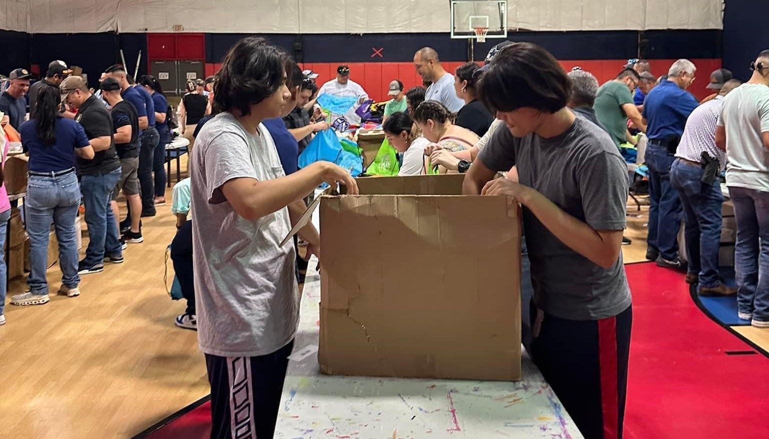 A group of people are standing around a table in a gym.