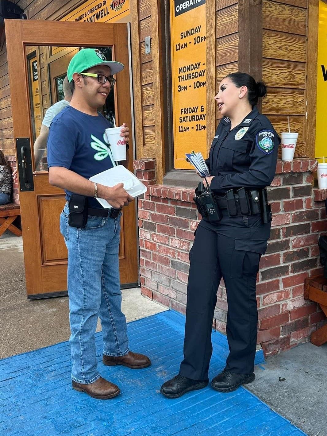 A man and a police officer are talking outside of a restaurant.