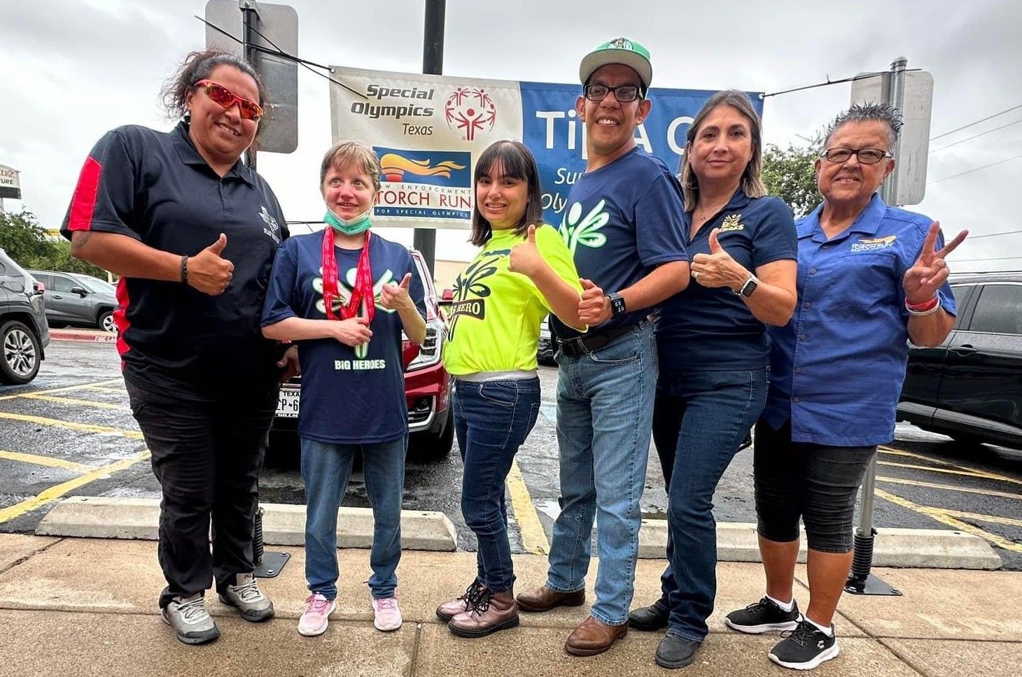 A group of people are posing for a picture in a parking lot.