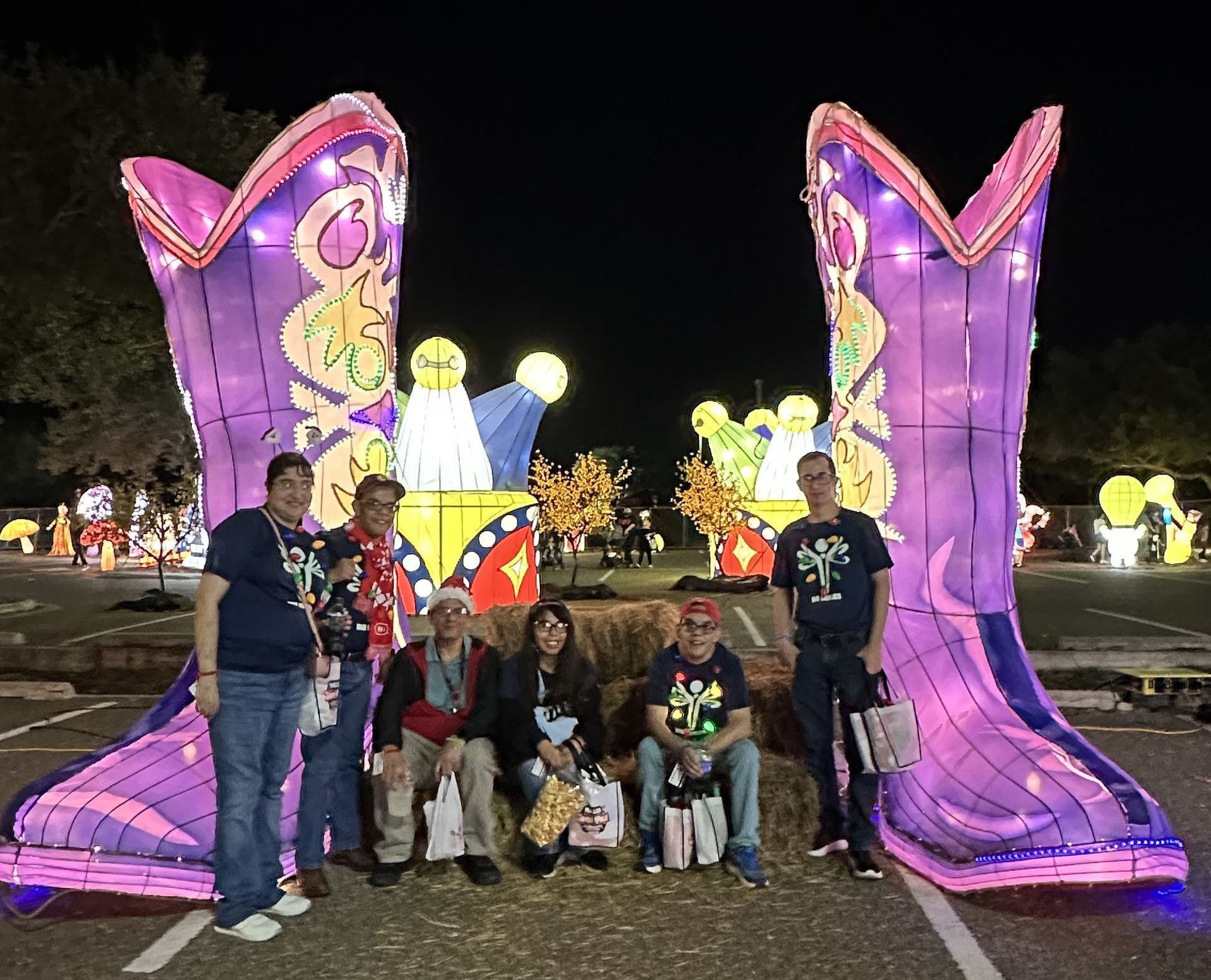 A group of people are posing for a picture in front of a pair of giant cowboy boots.