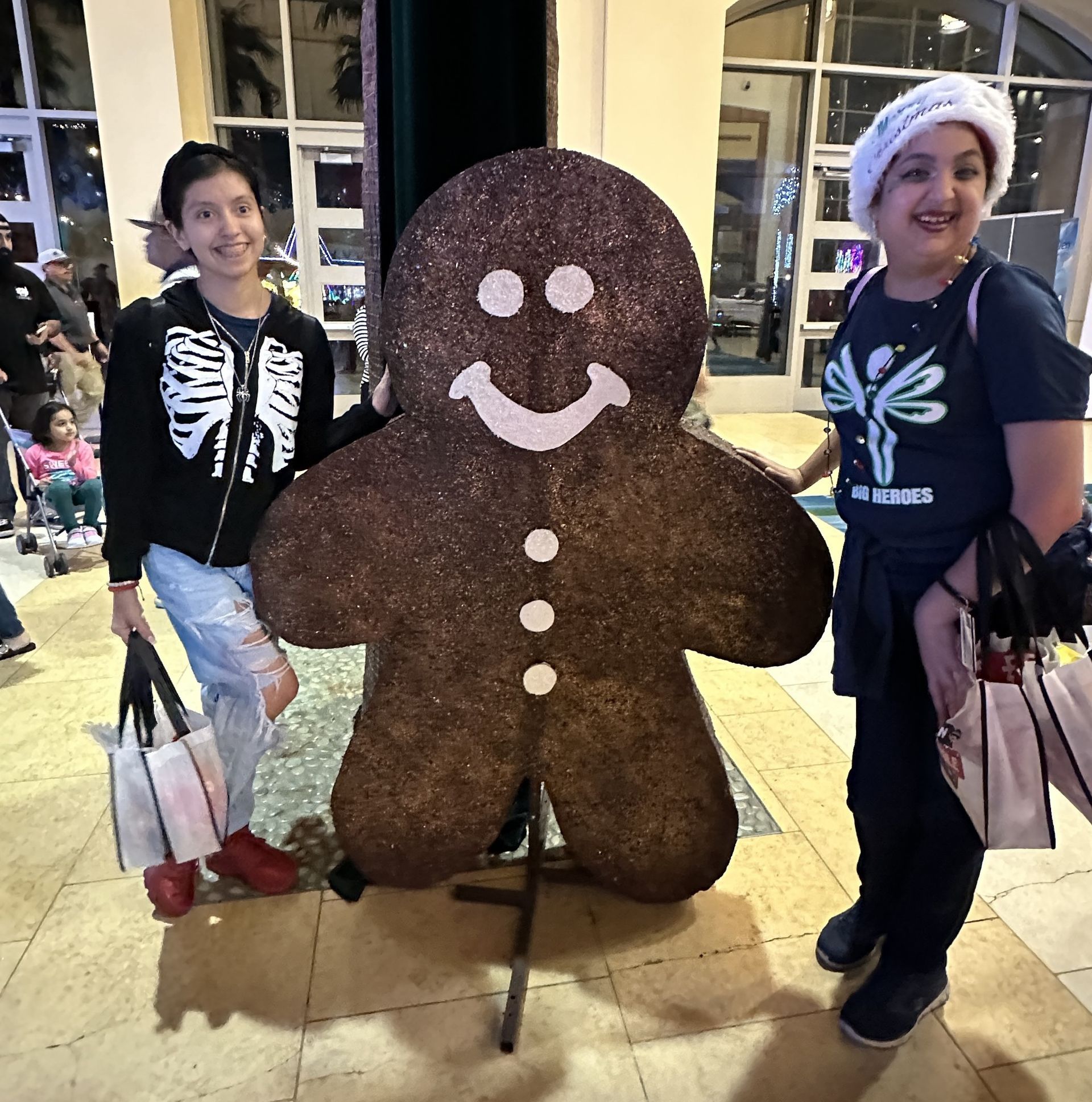 Two women standing next to a giant gingerbread man