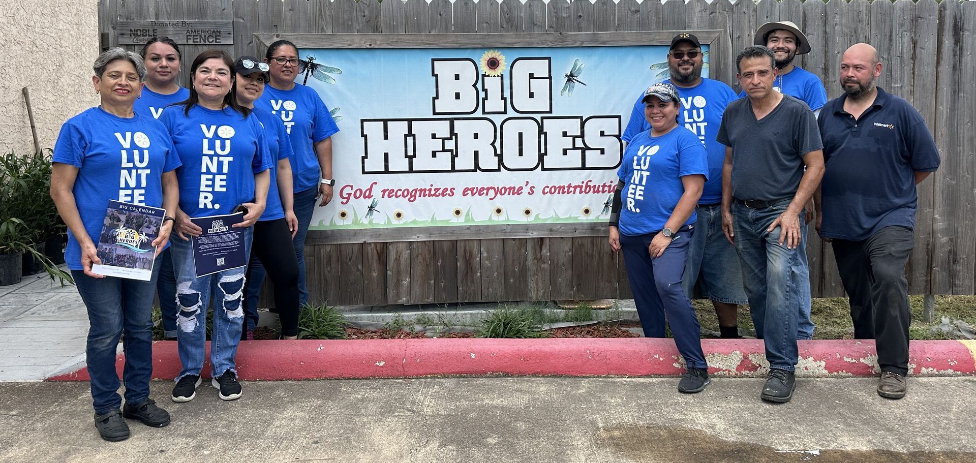 A group of people standing in front of a sign that says big heroes.