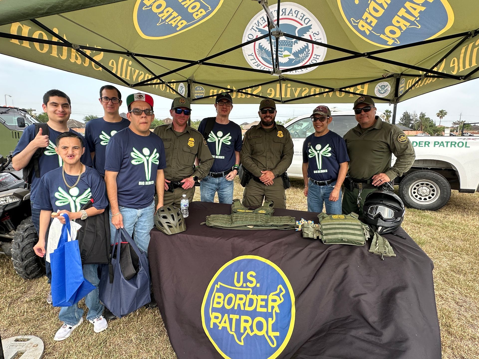 A group of men are standing around a table under a tent.