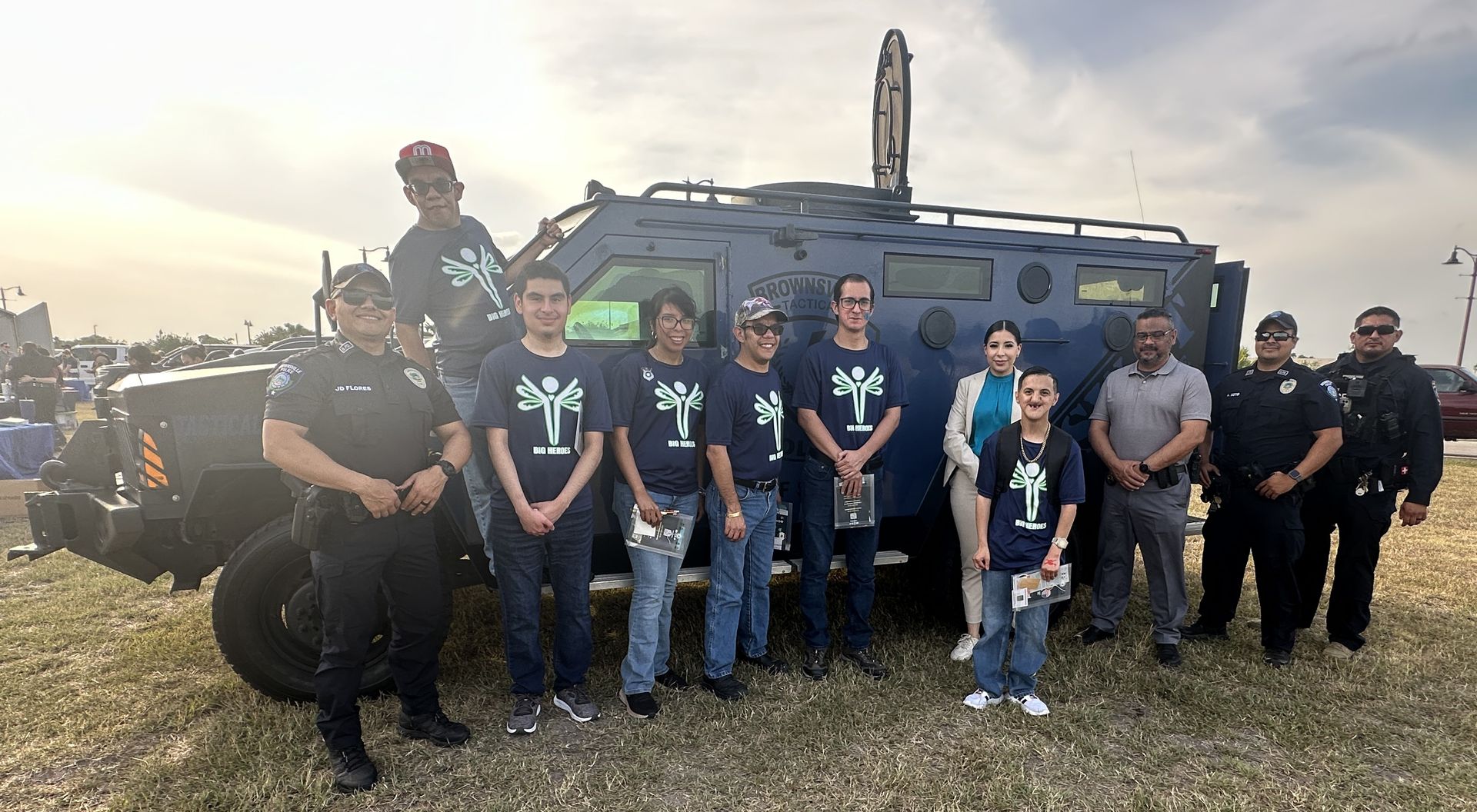 A group of people standing in front of a military vehicle.