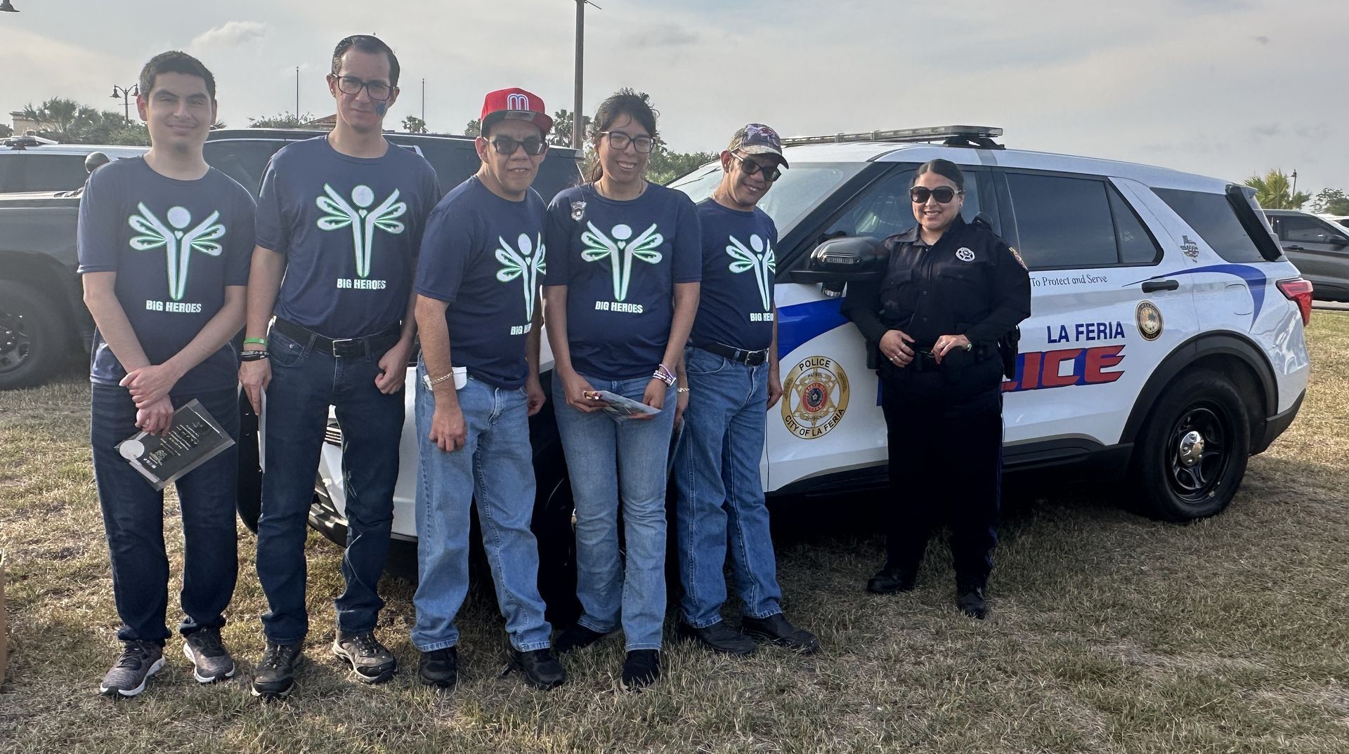 A group of people are posing for a picture in front of a police car.