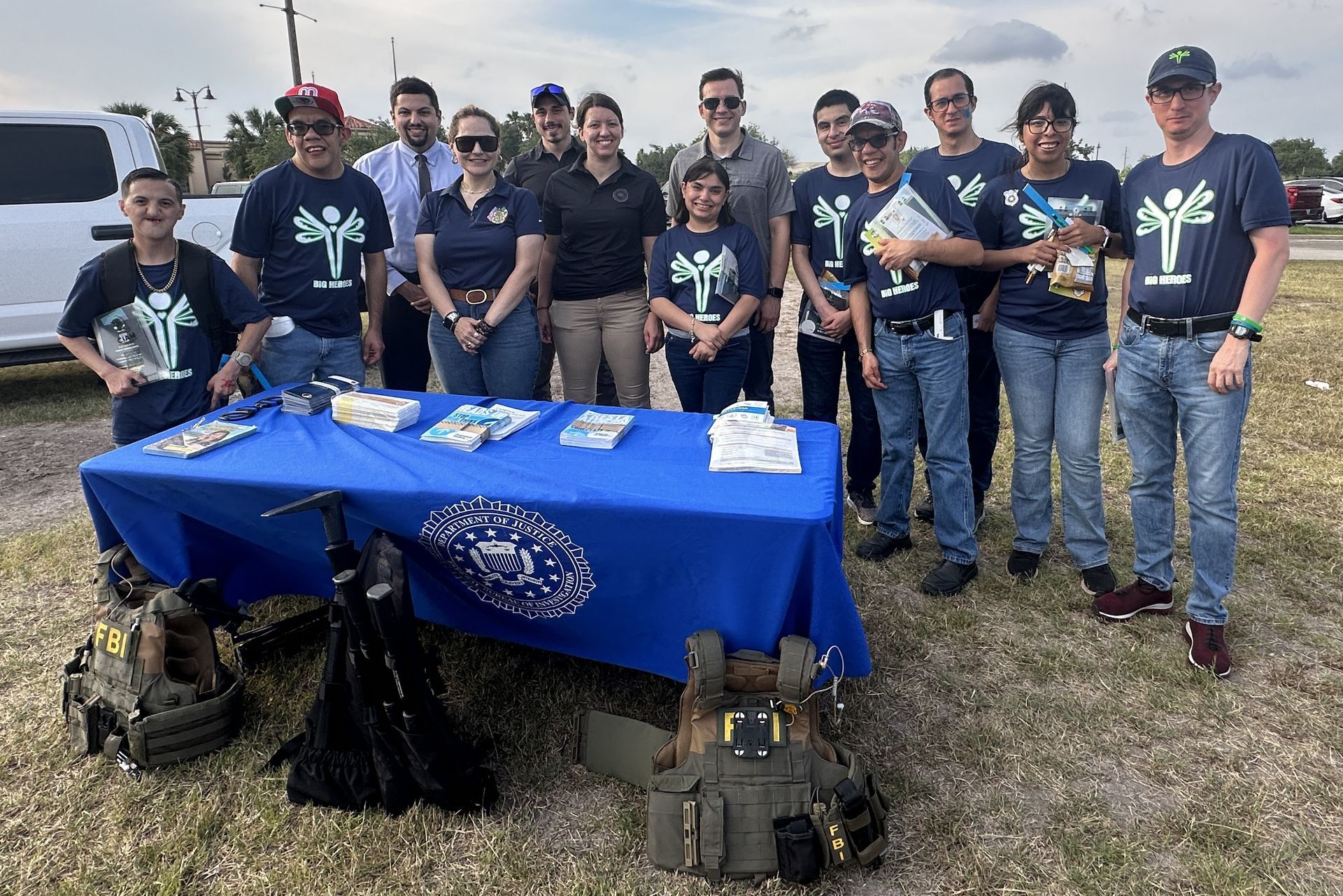 A group of people standing around a table with a blue table cloth.