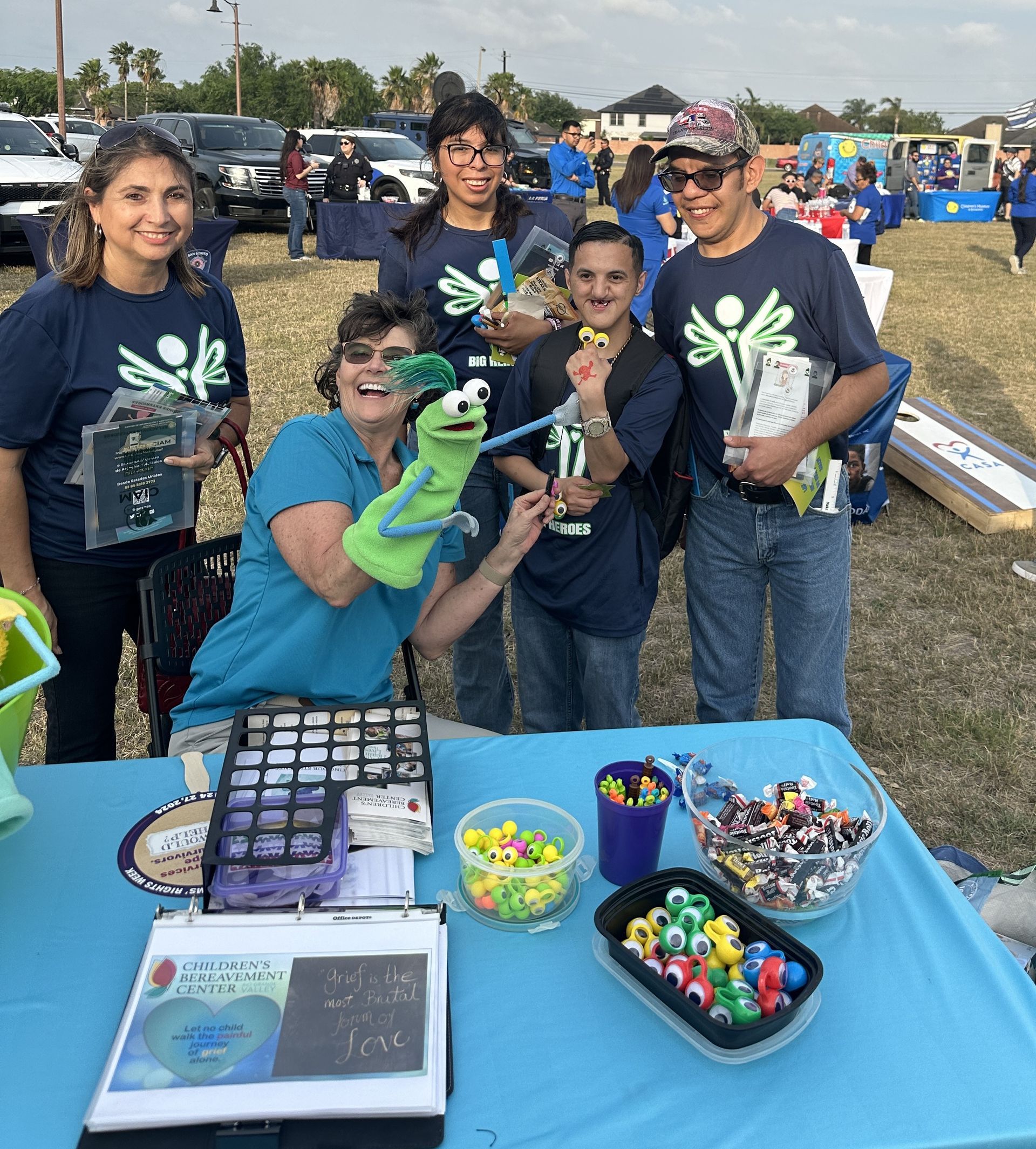 A group of people standing around a table with a puppet on it.