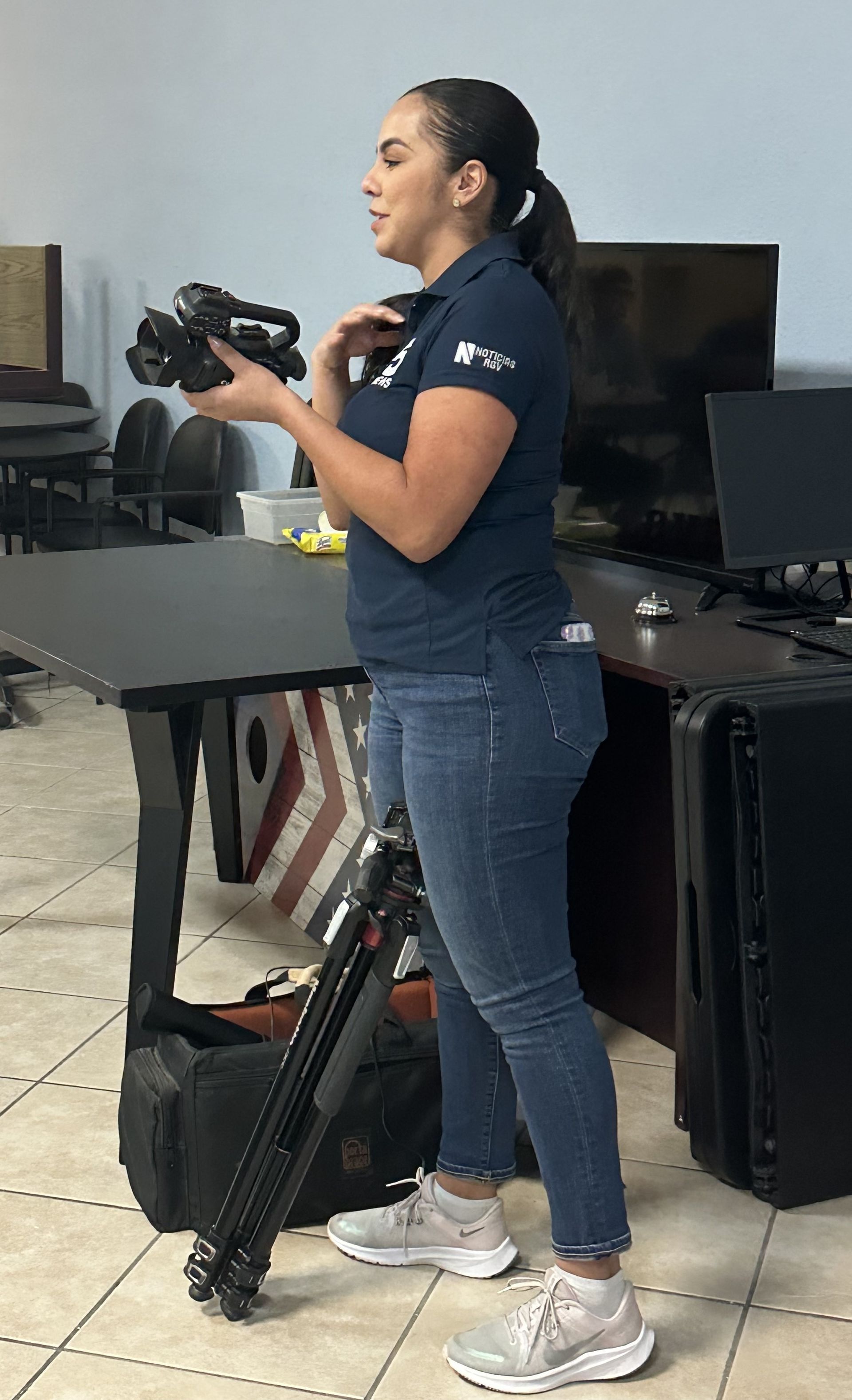 A woman is standing in a room holding a camera.