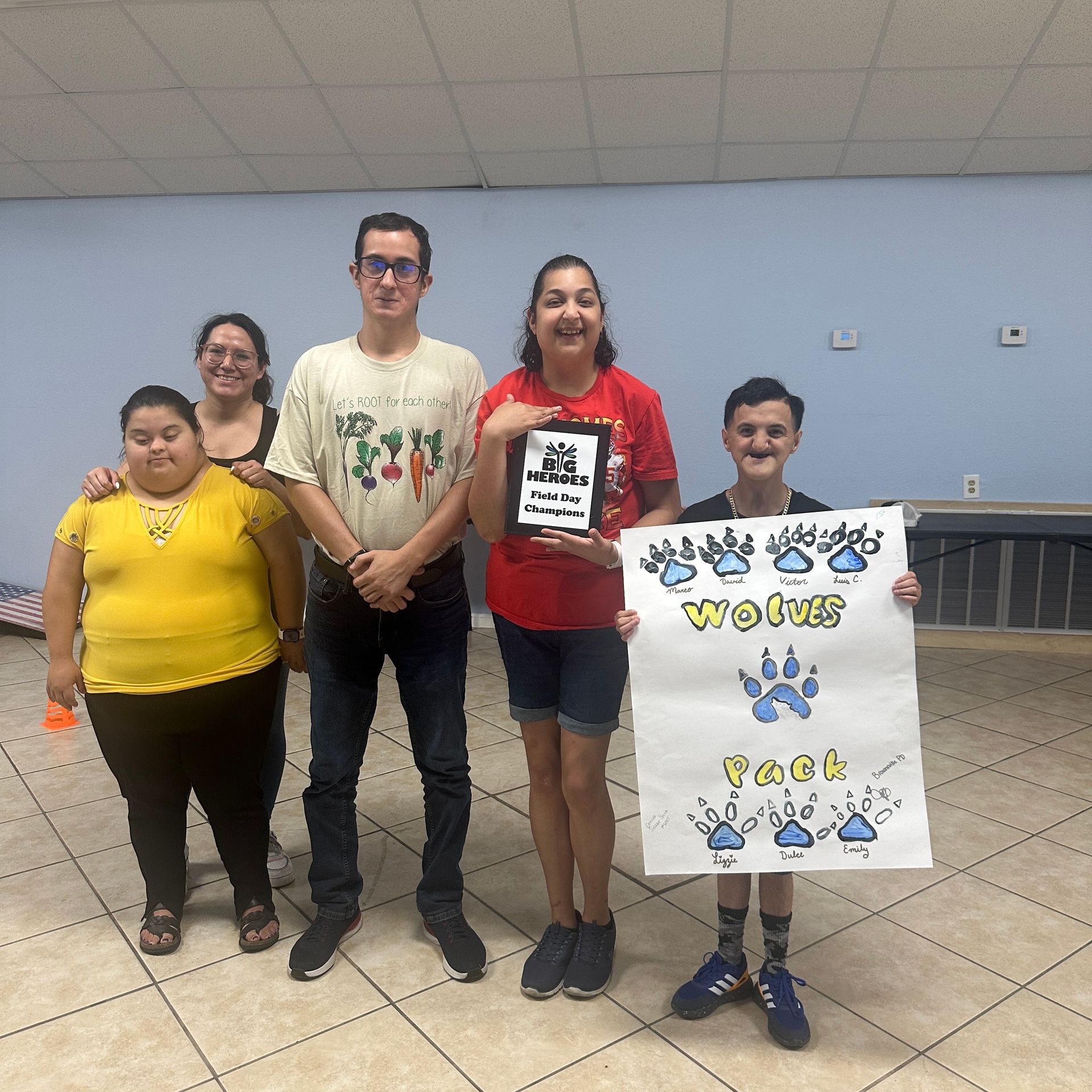 A group of people are posing for a picture and one of them is holding a sign that says 