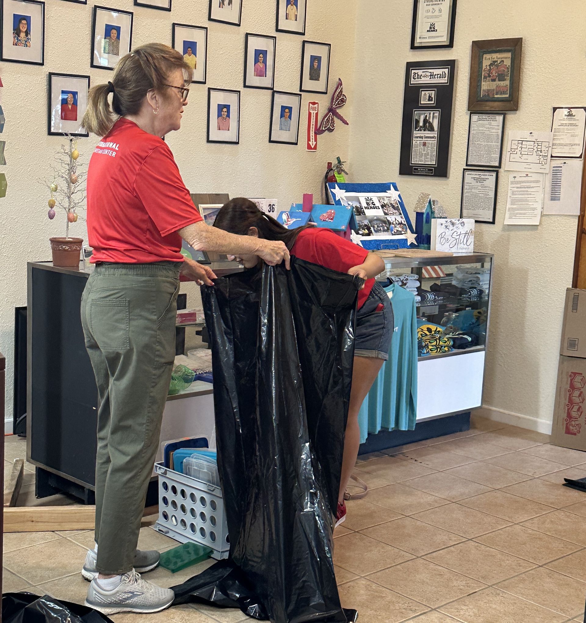 A woman in a red shirt is holding a black bag