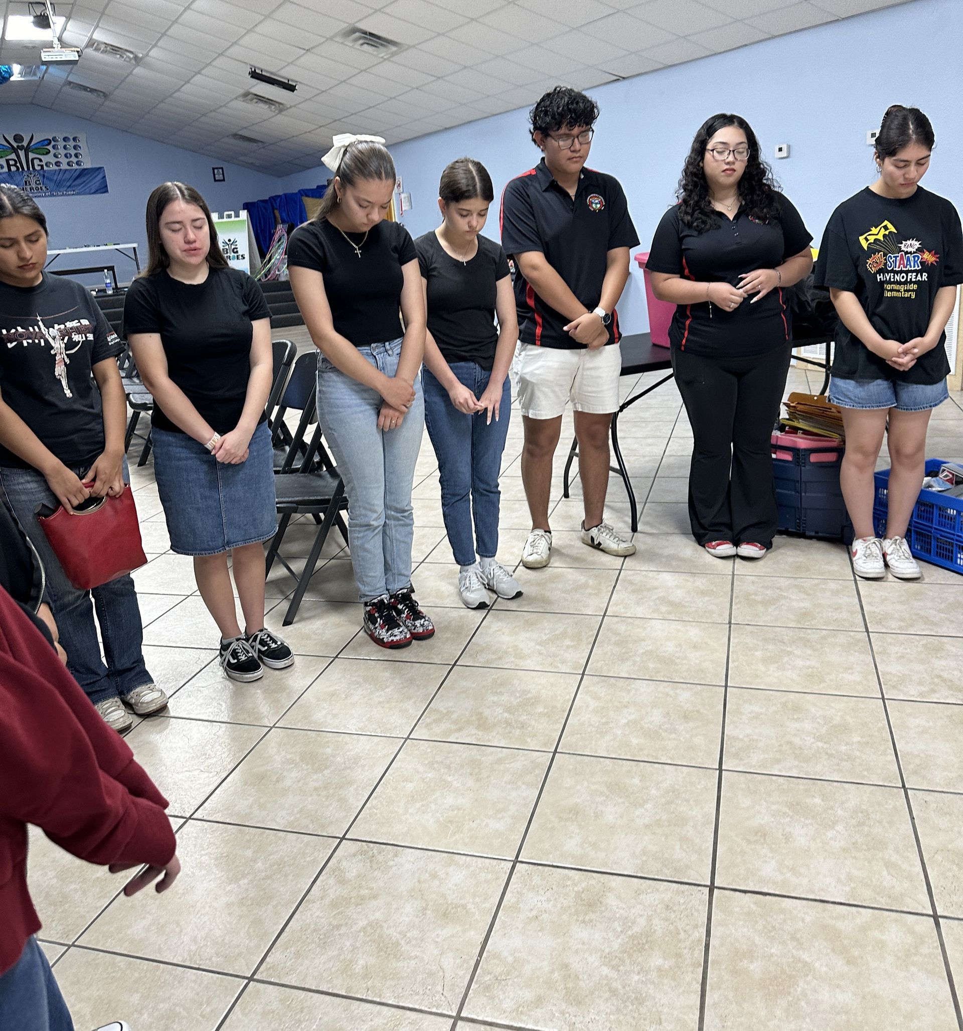 A group of people are standing in a room and one of them is wearing a shirt that says i love you