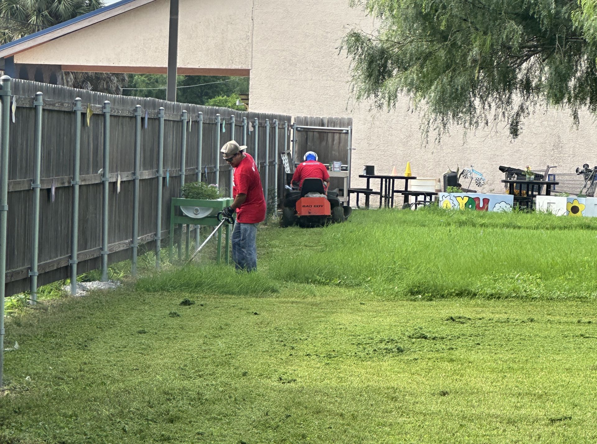 A man is mowing the grass in a backyard with a lawn mower.