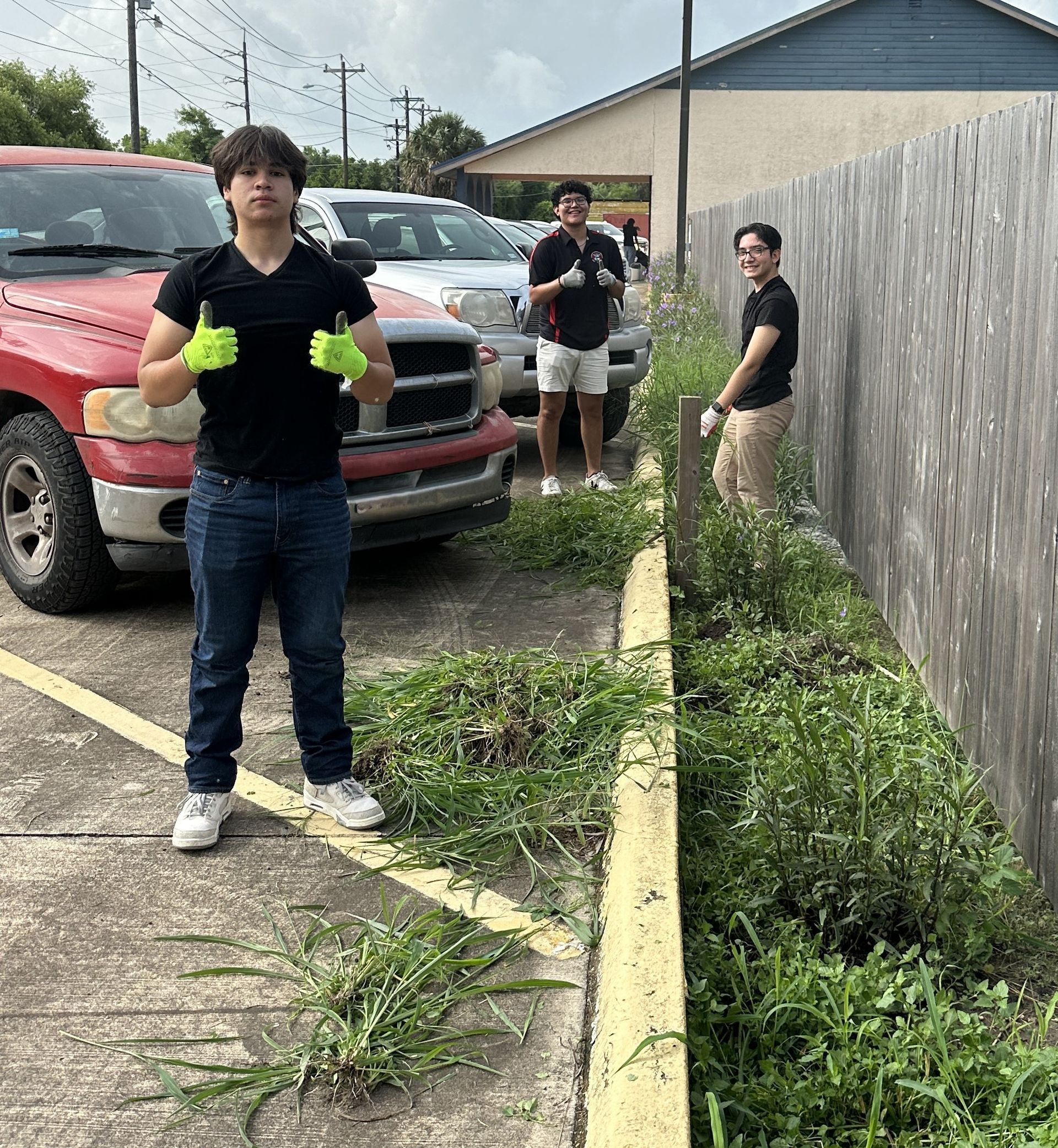 A group of people are standing next to a fence and a truck.
