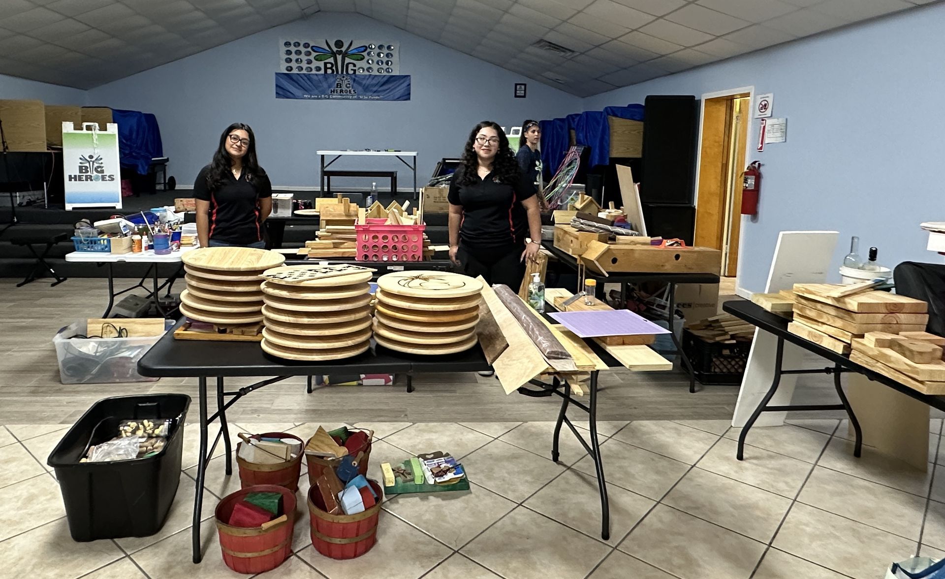 Two women are standing in front of a table with plates on it.