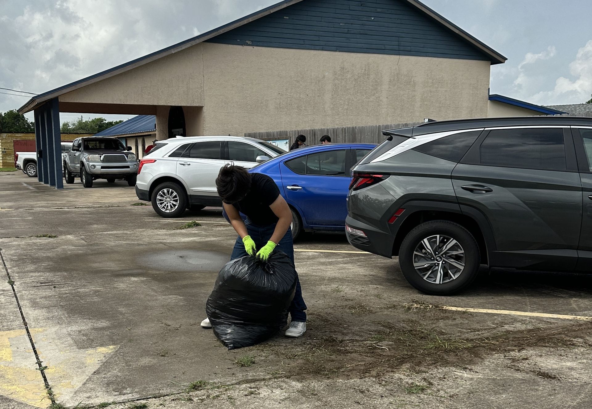 A man is holding a trash bag in a parking lot.