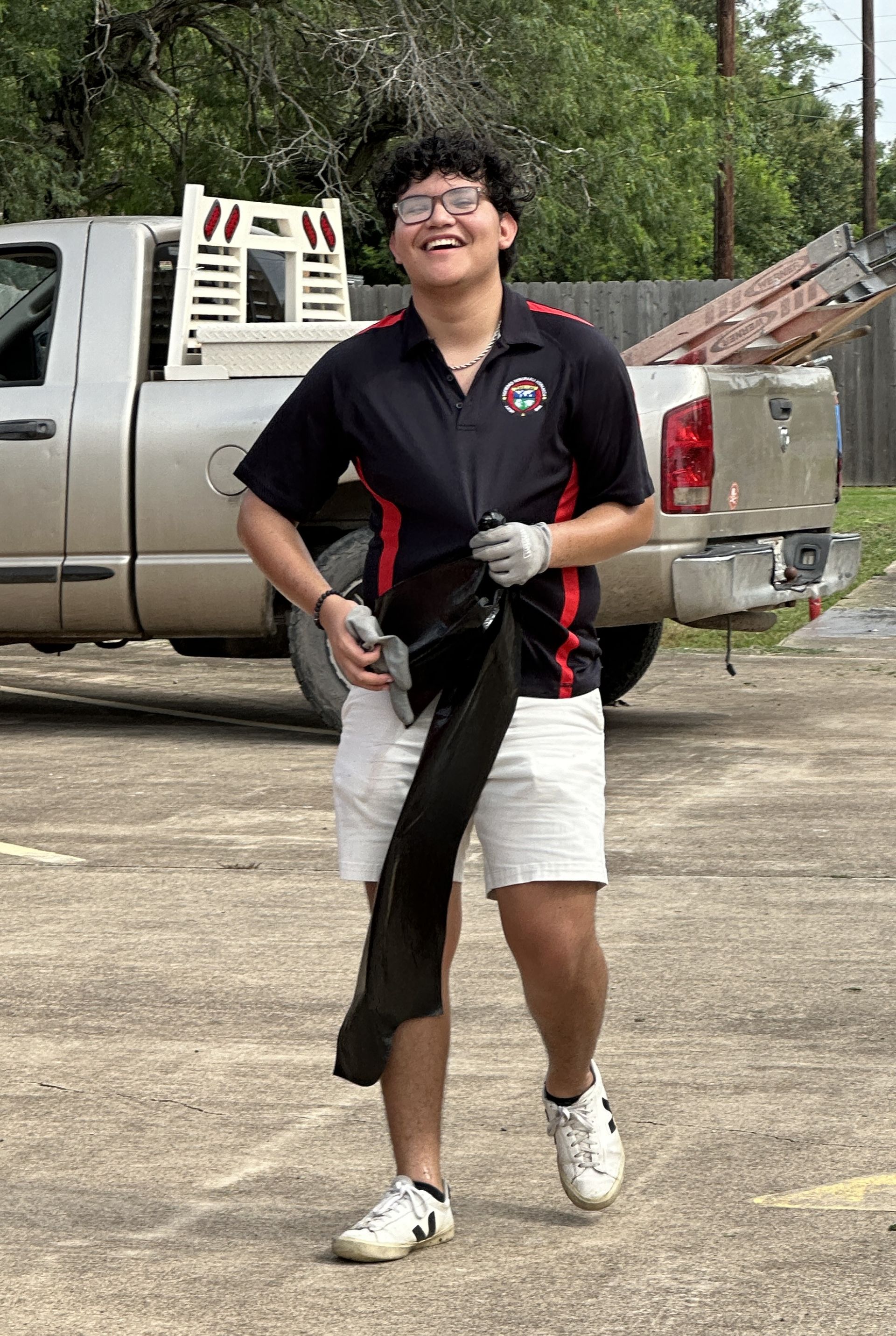 A young man is standing in front of a truck in a parking lot.