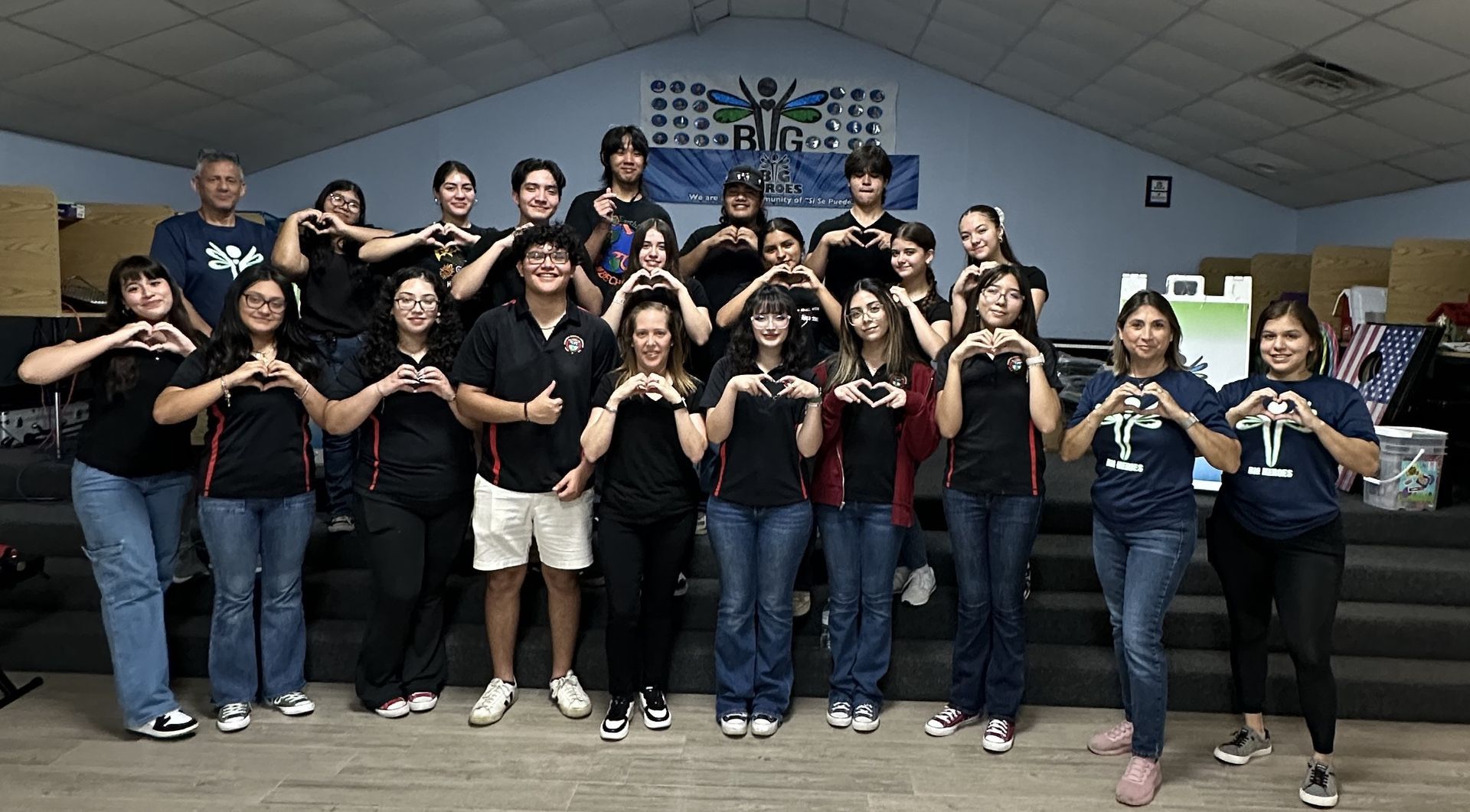 A group of people are making a heart shape with their hands.