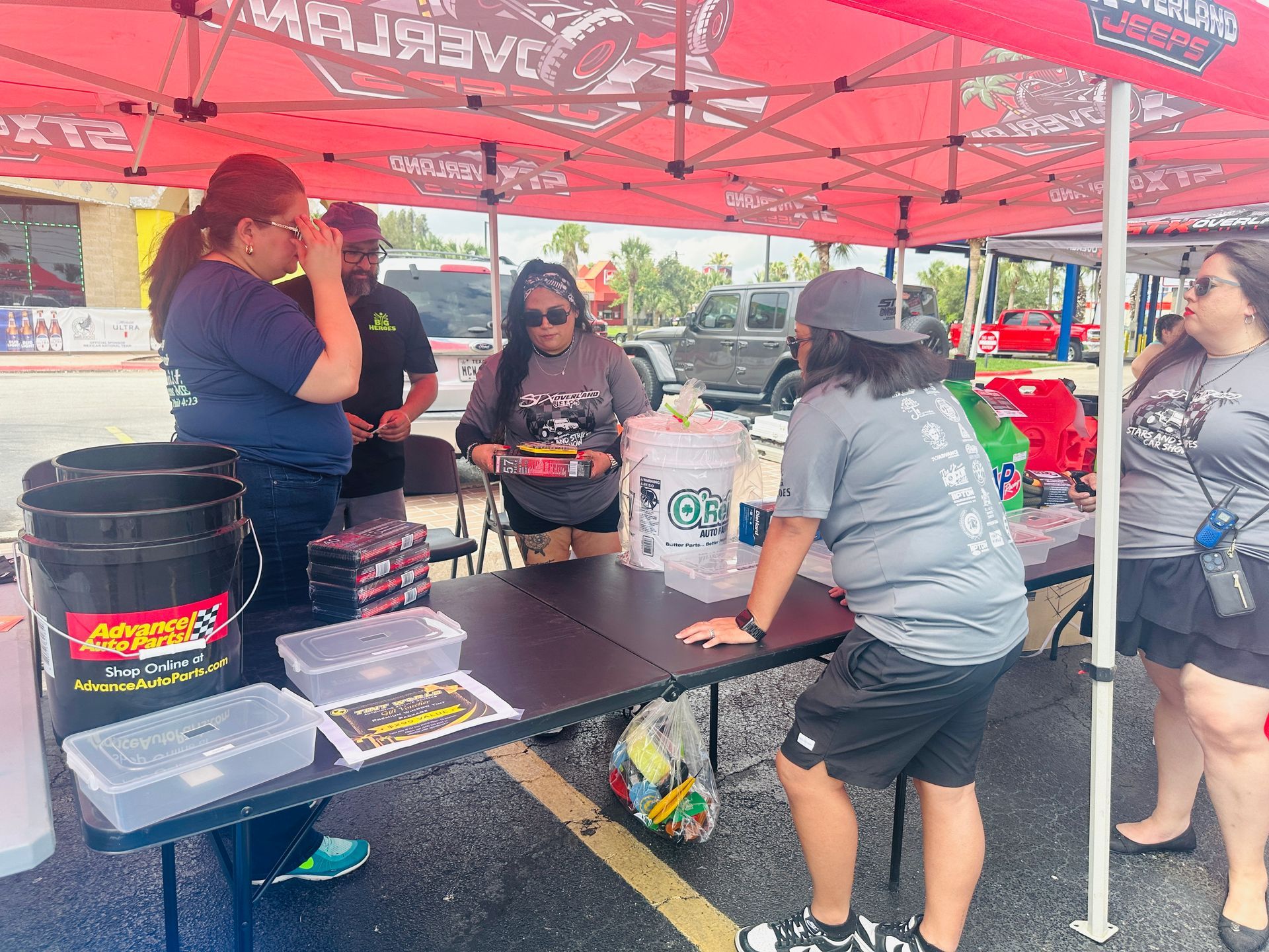 A group of people are standing around a table under a tent.