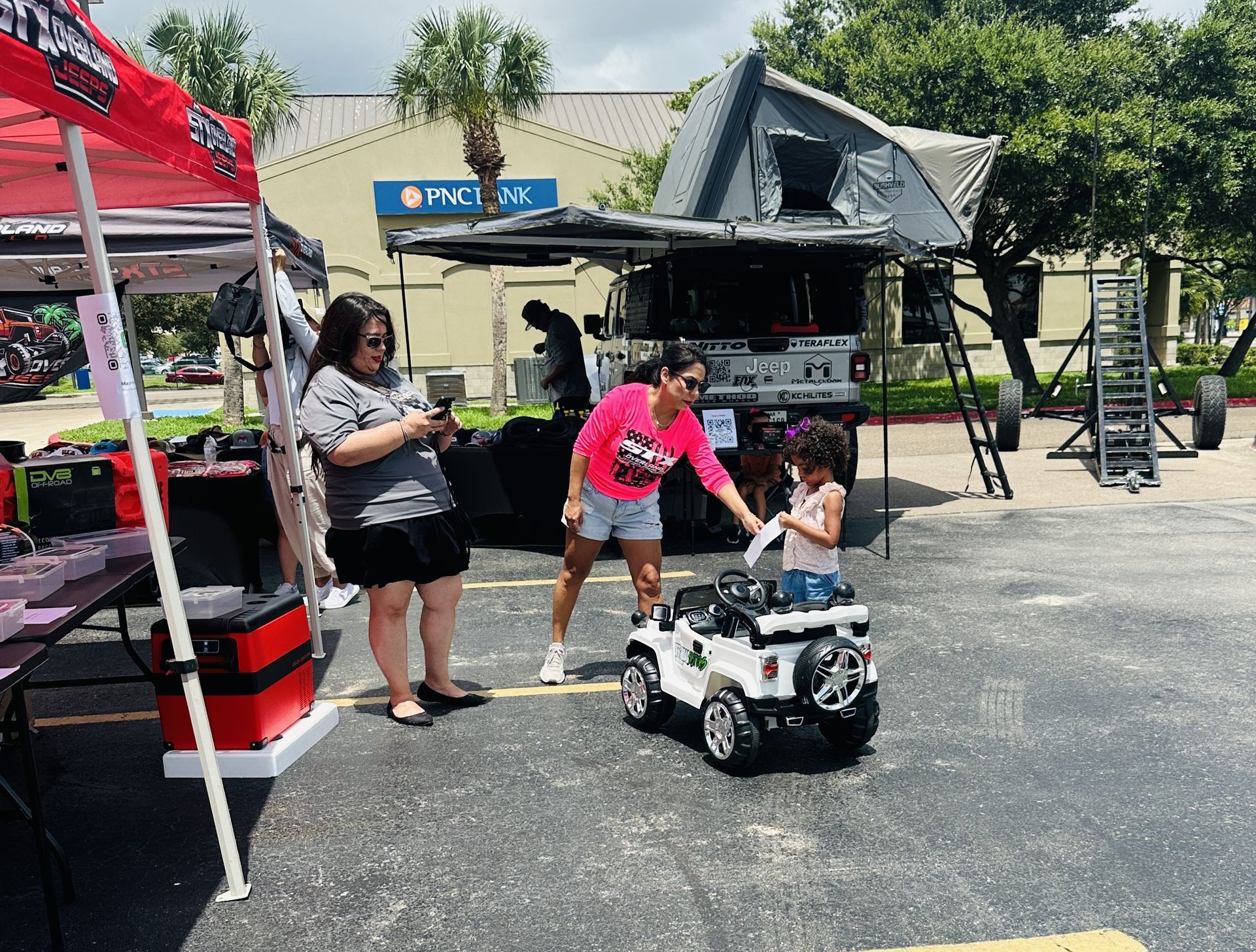 A little girl is playing with a toy car in a parking lot.