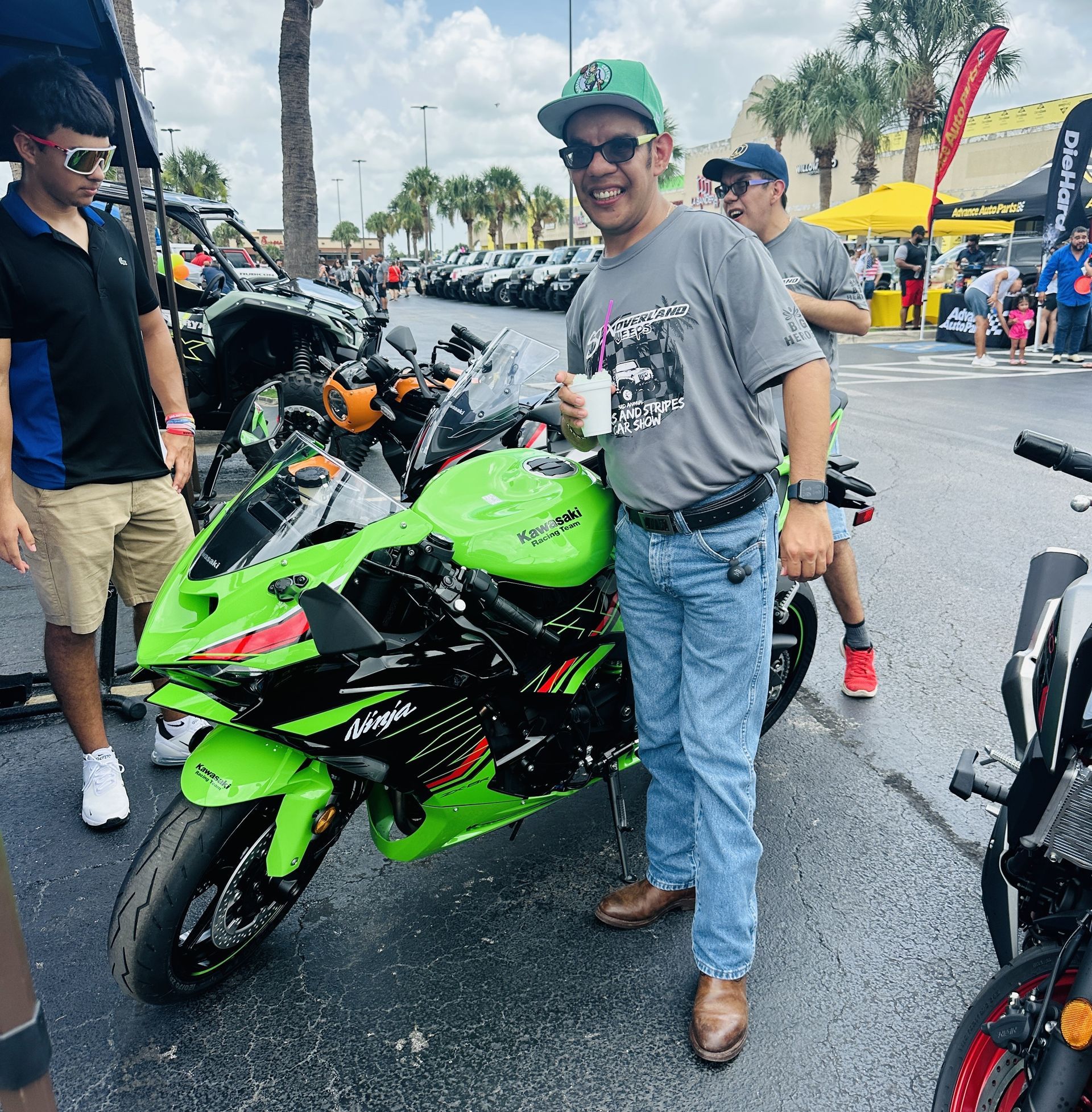 A man is standing next to a green motorcycle