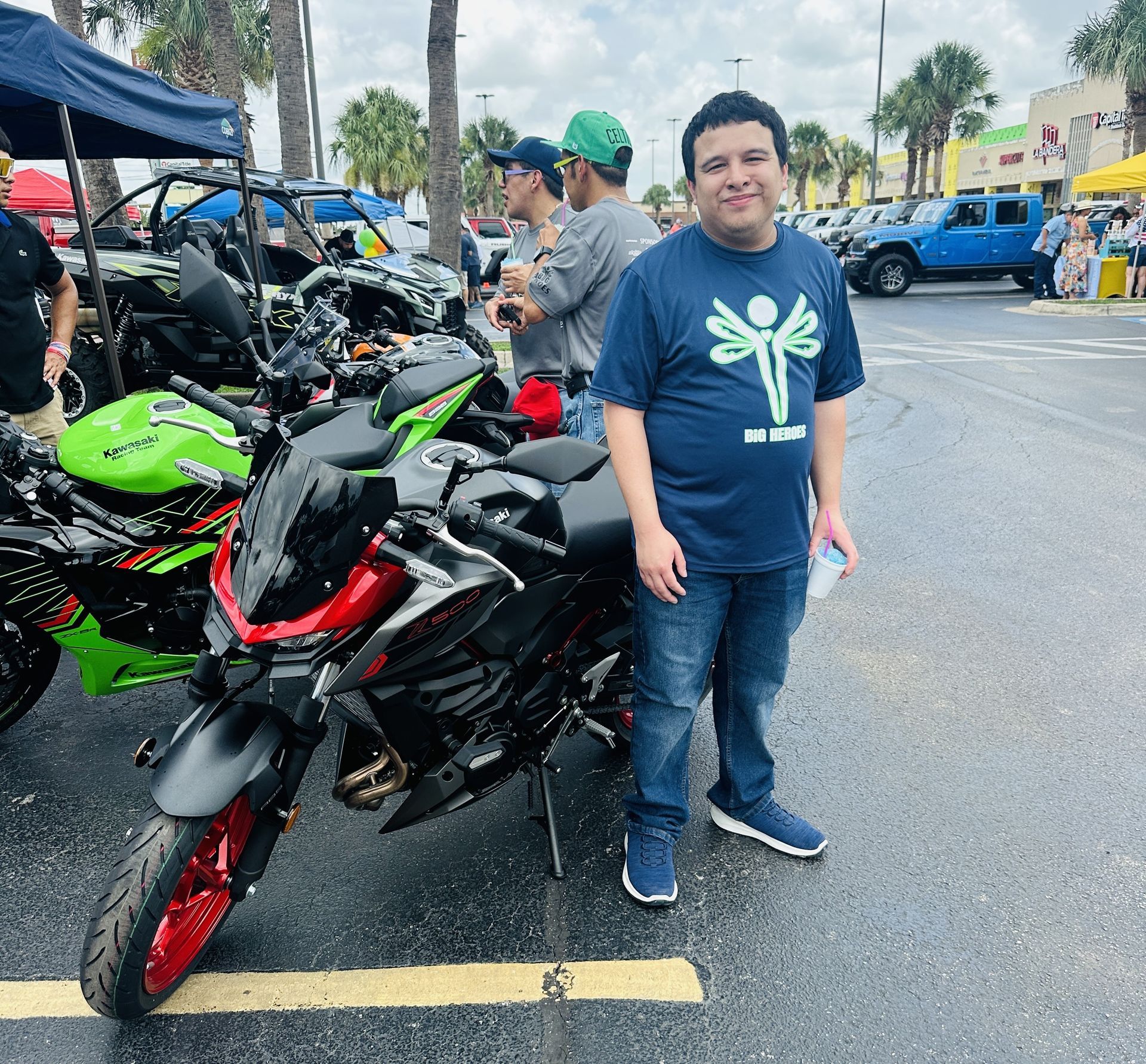 A man in a blue shirt is standing next to a motorcycle