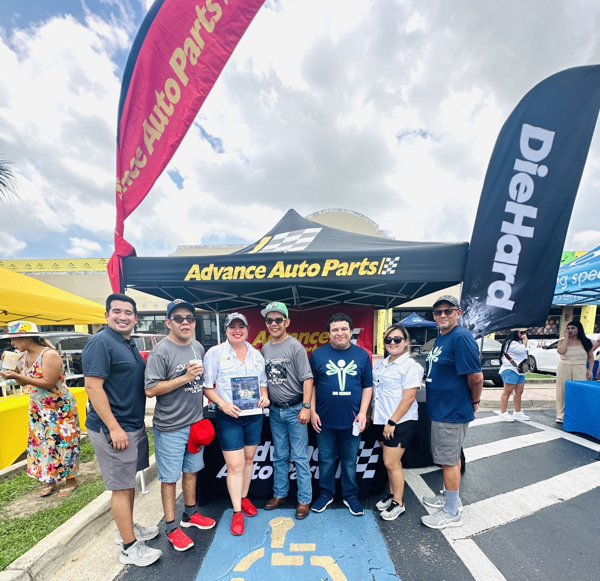 A group of people standing in front of an advance auto parts booth