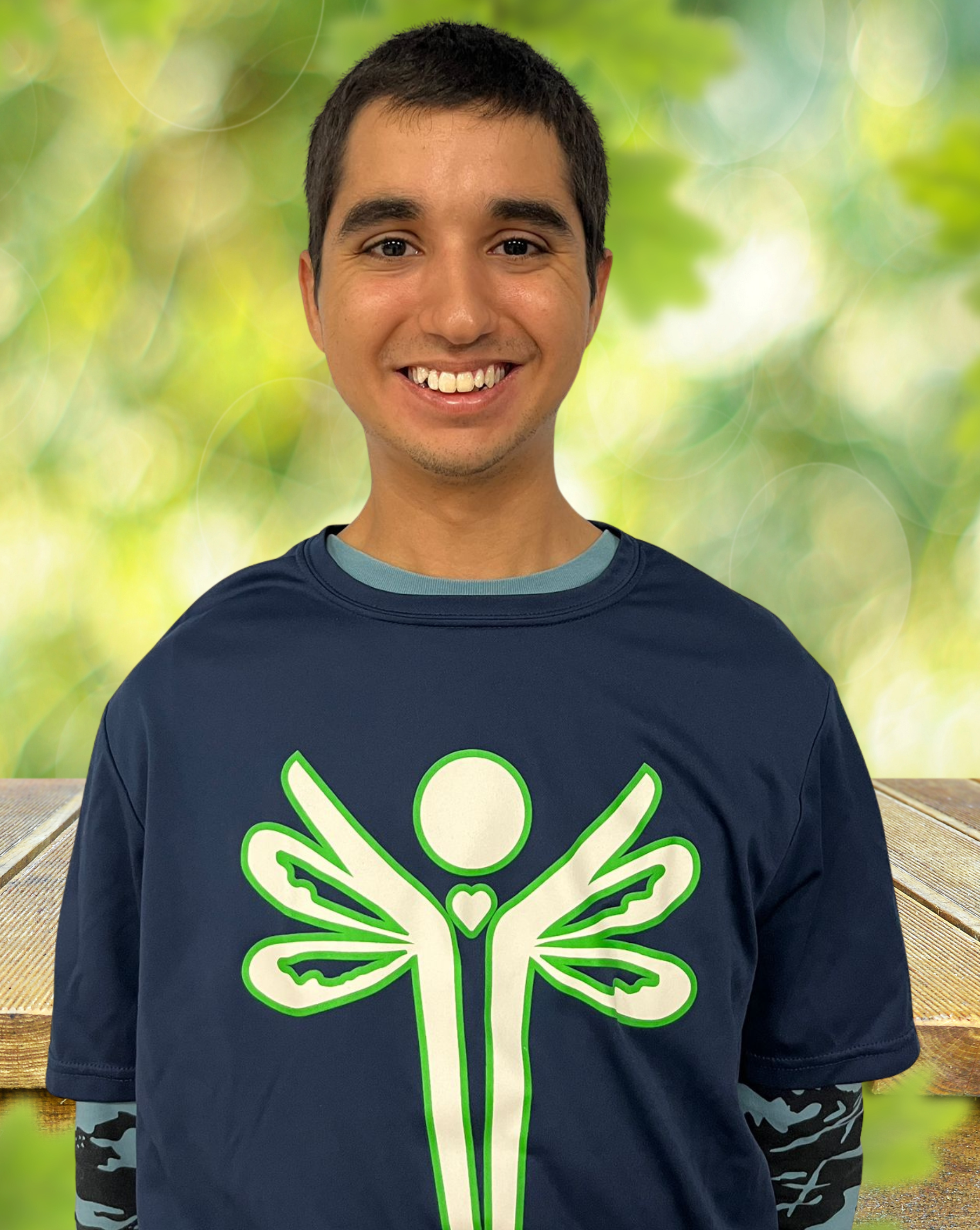 Smiling young man in blue shirt with green logo, outdoors.