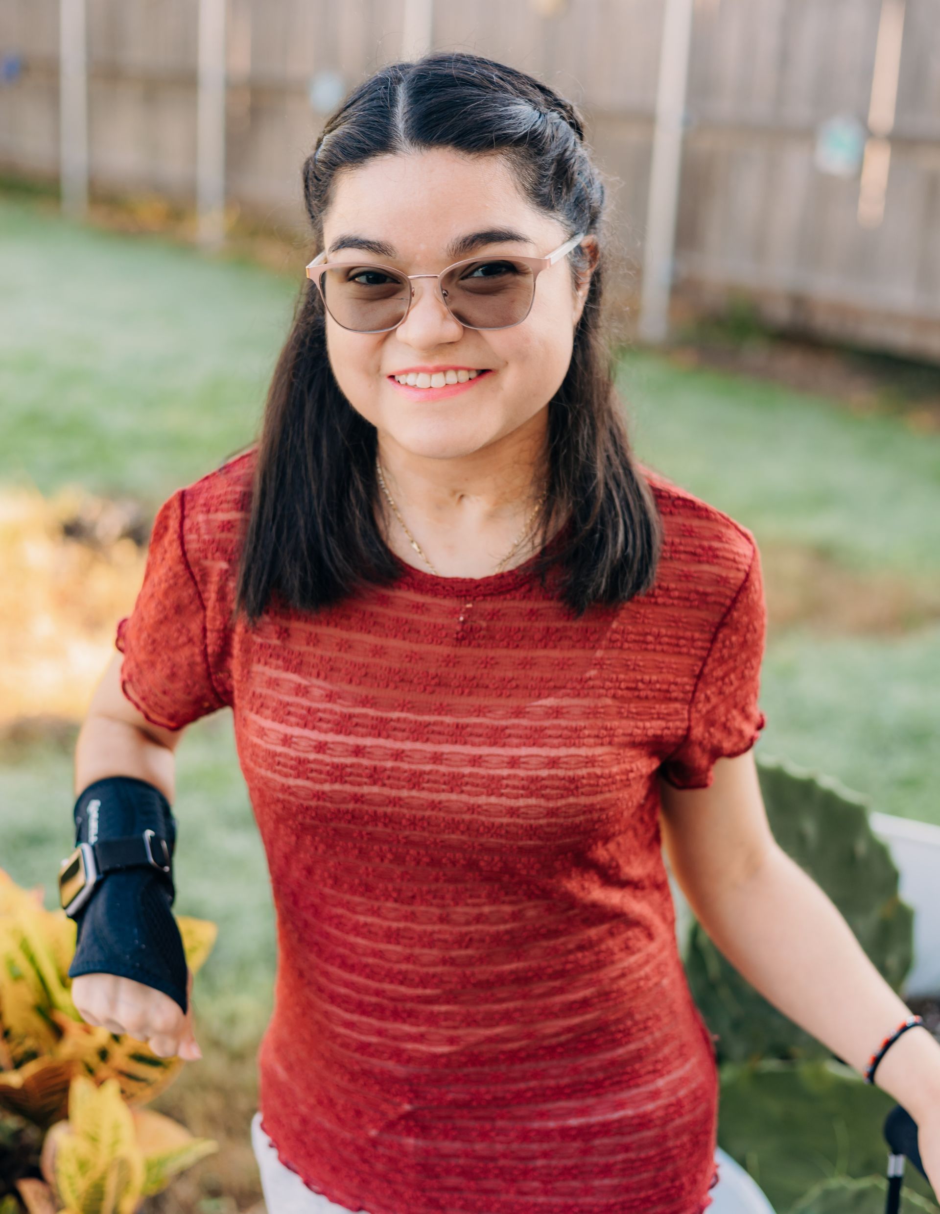 A woman with a prosthetic arm is wearing sunglasses and a red shirt.