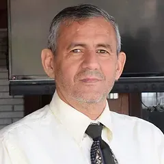 A man in a white shirt and tie is standing in front of a television.