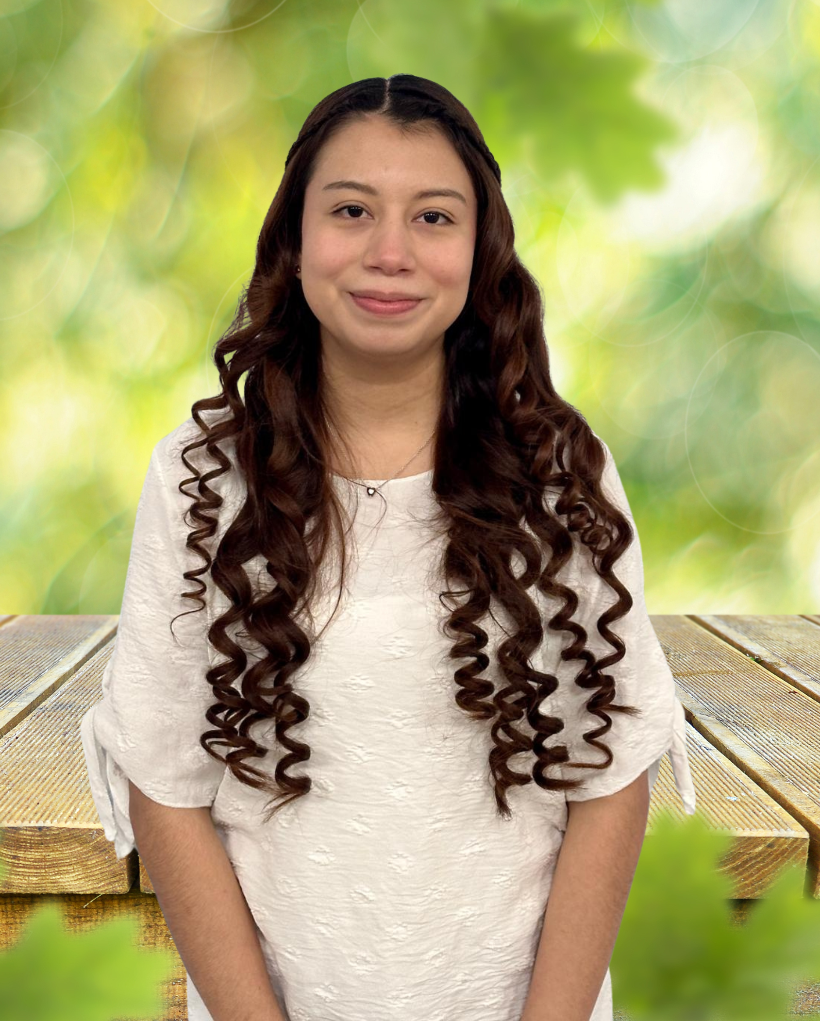 A woman with long curly hair is standing in front of a wooden table.