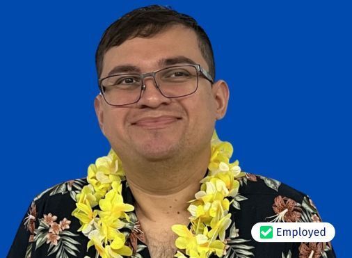 A man wearing glasses and a lei around his neck is smiling.