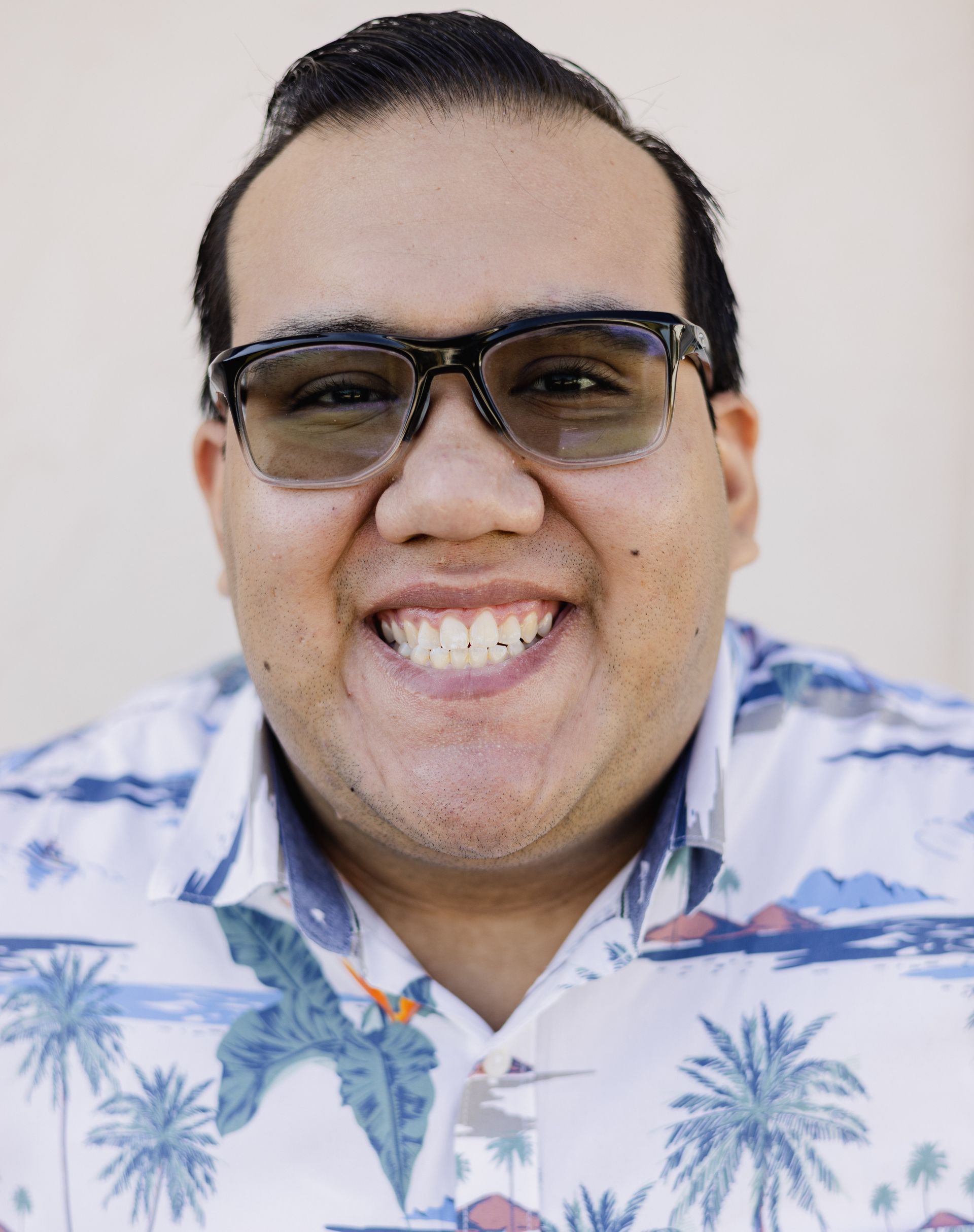 A man wearing glasses and a blue shirt is smiling for the camera.