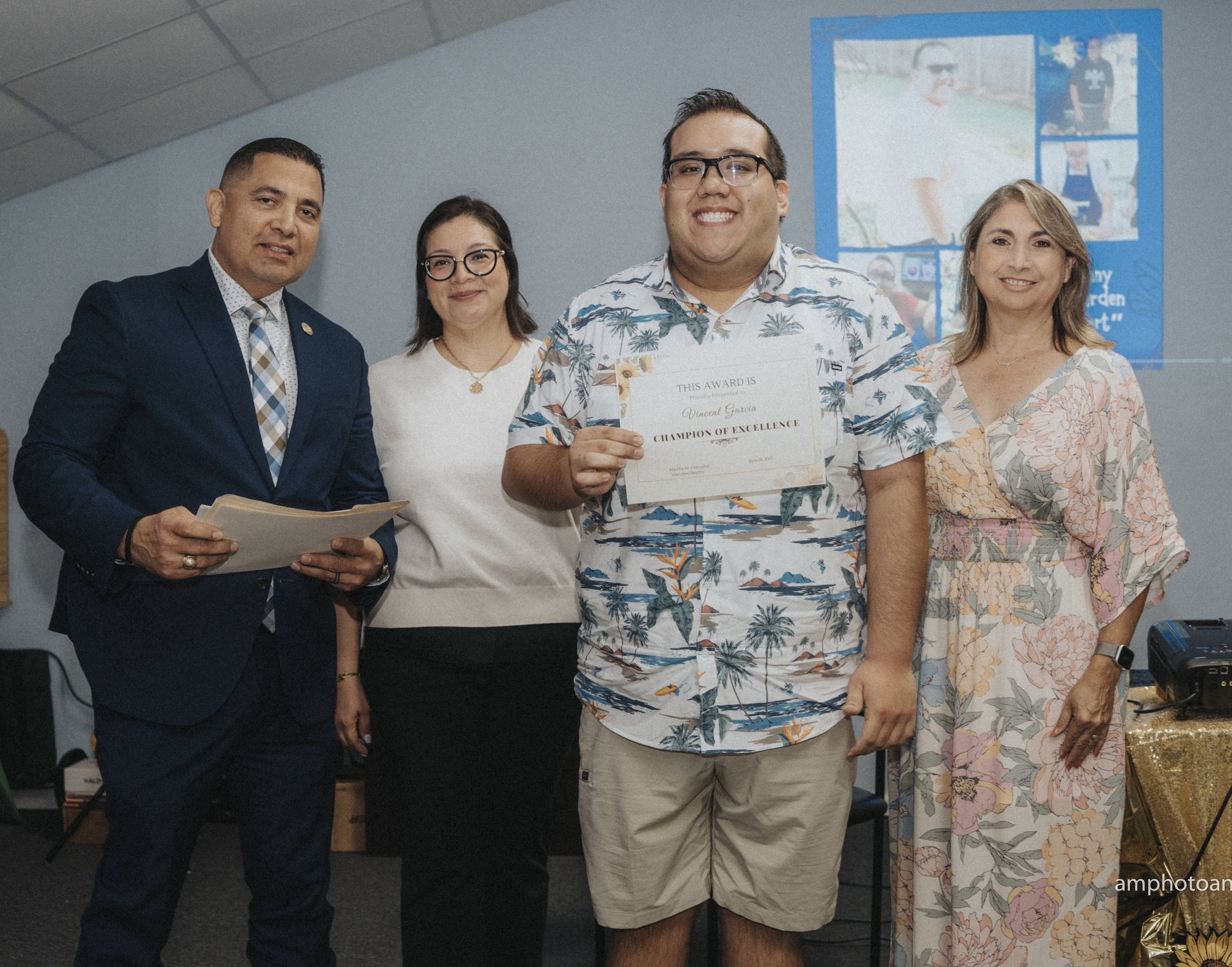 People at an award ceremony. A man receives a certificate. Others watch in a casual setting.