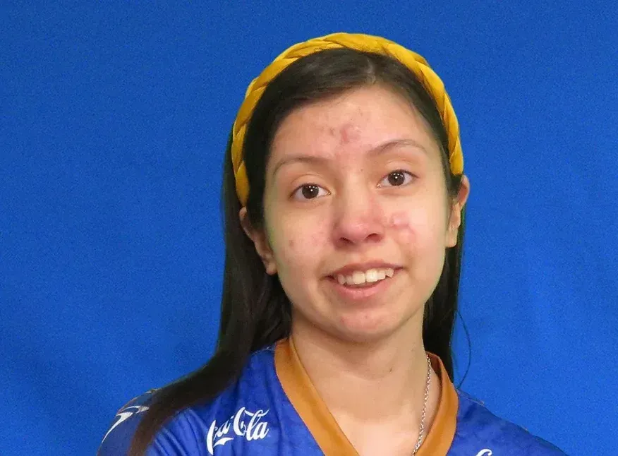 A woman wearing a headband and a coca cola shirt smiles for the camera.