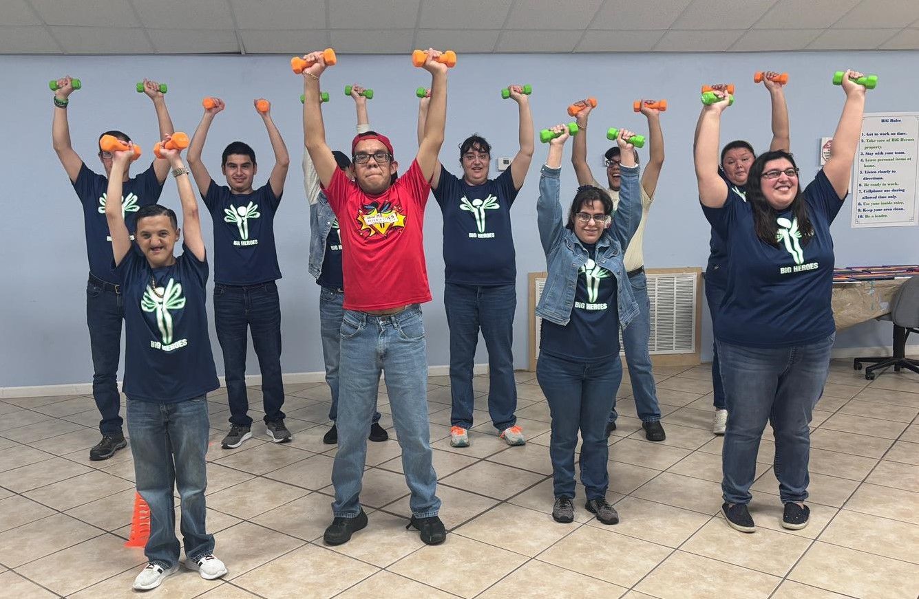 A group of people are standing in a room holding dumbbells in their hands.
